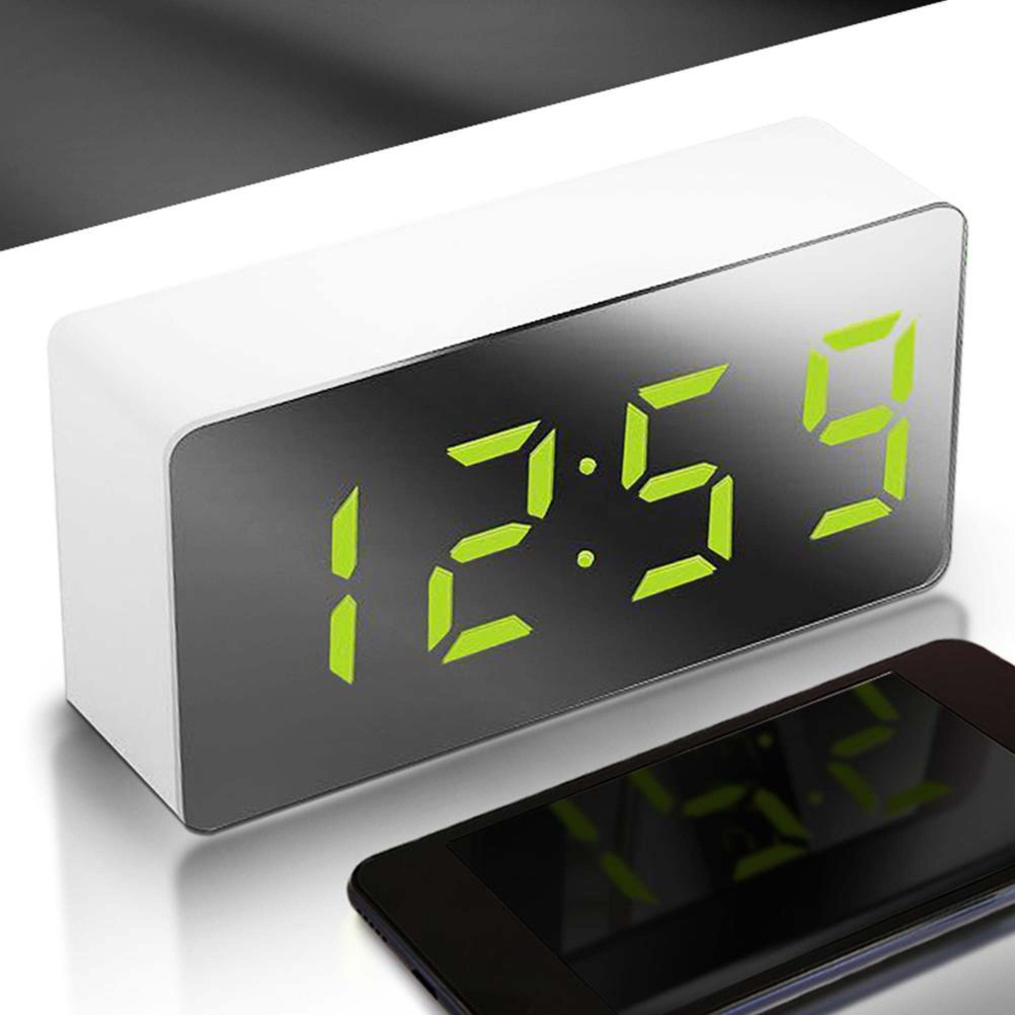 Ein digitaler Wecker mit grüner LED-Anzeige zeigt 12:59 an. Daneben liegt ein Smartphone.