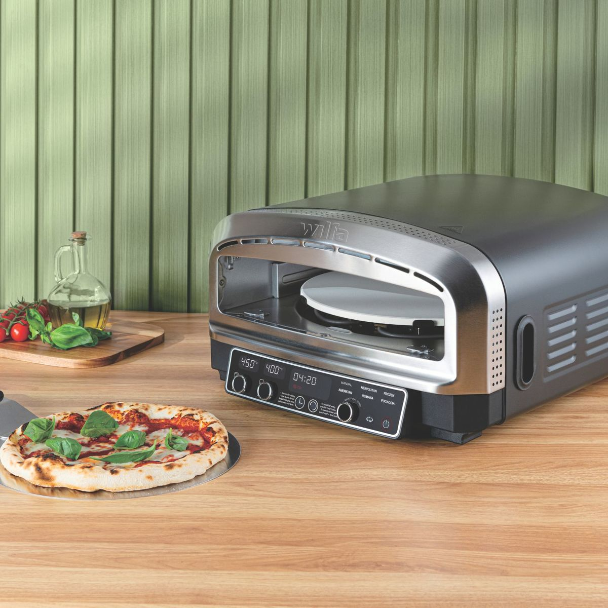 Ein fertiger Margherita-Pizzaboden und ein Toaster-Ofen stehen auf einem Holztisch.