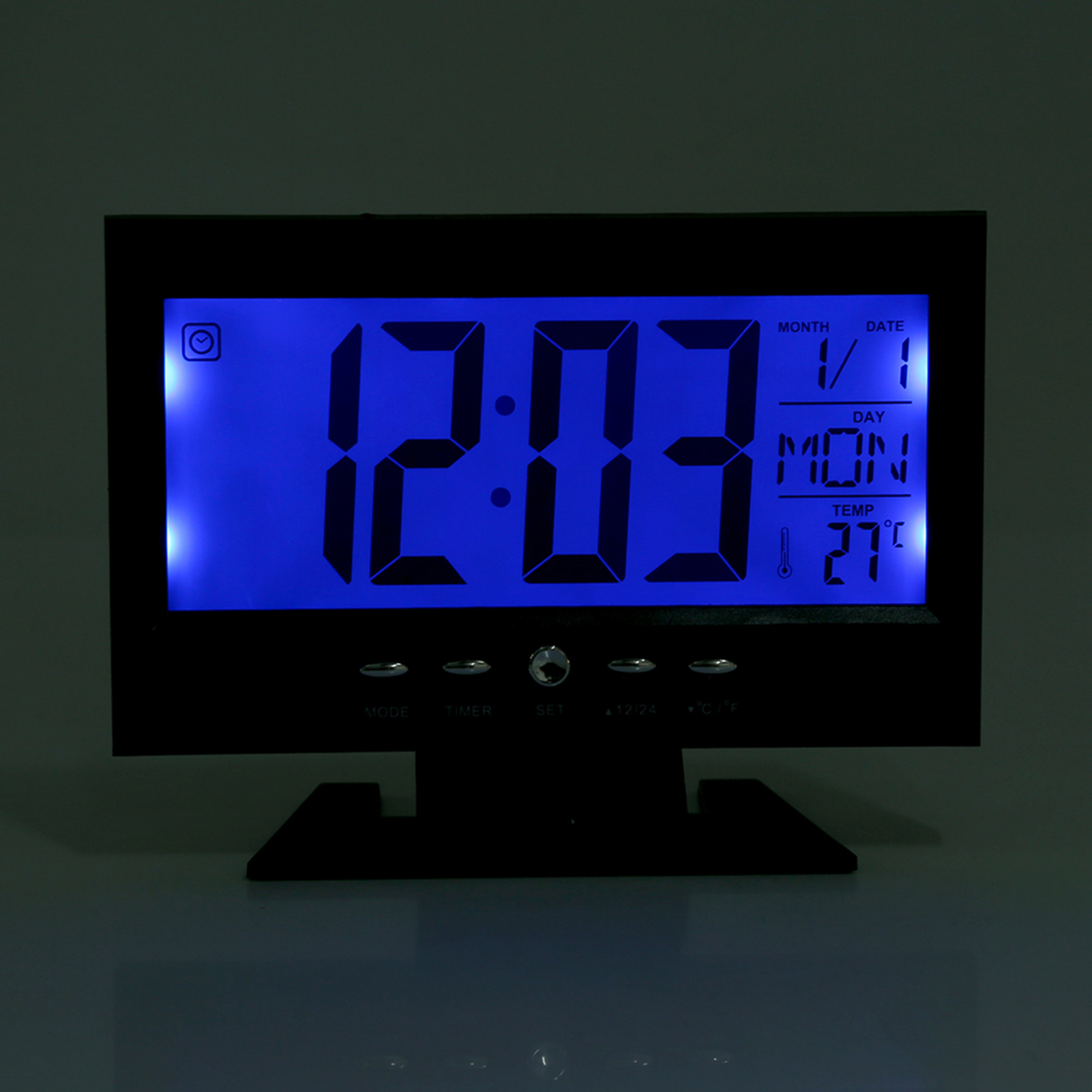 Ein digitaler Wecker zeigt 12:03, Datum 1/1, Tag MON, Temperatur 27°C.