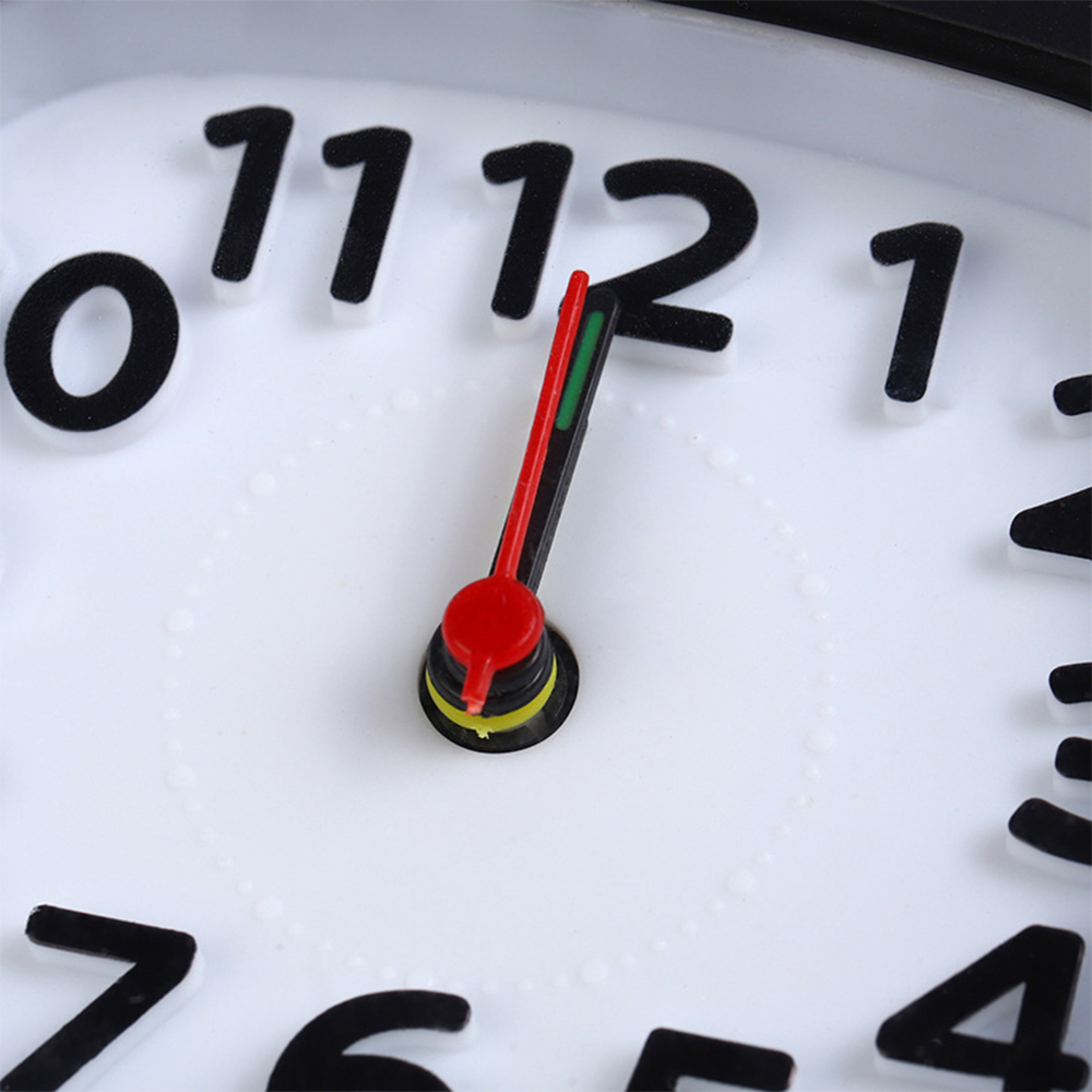 Nahaufnahme einer weißen Uhr mit schwarzen Ziffern und bunten Zeigern.