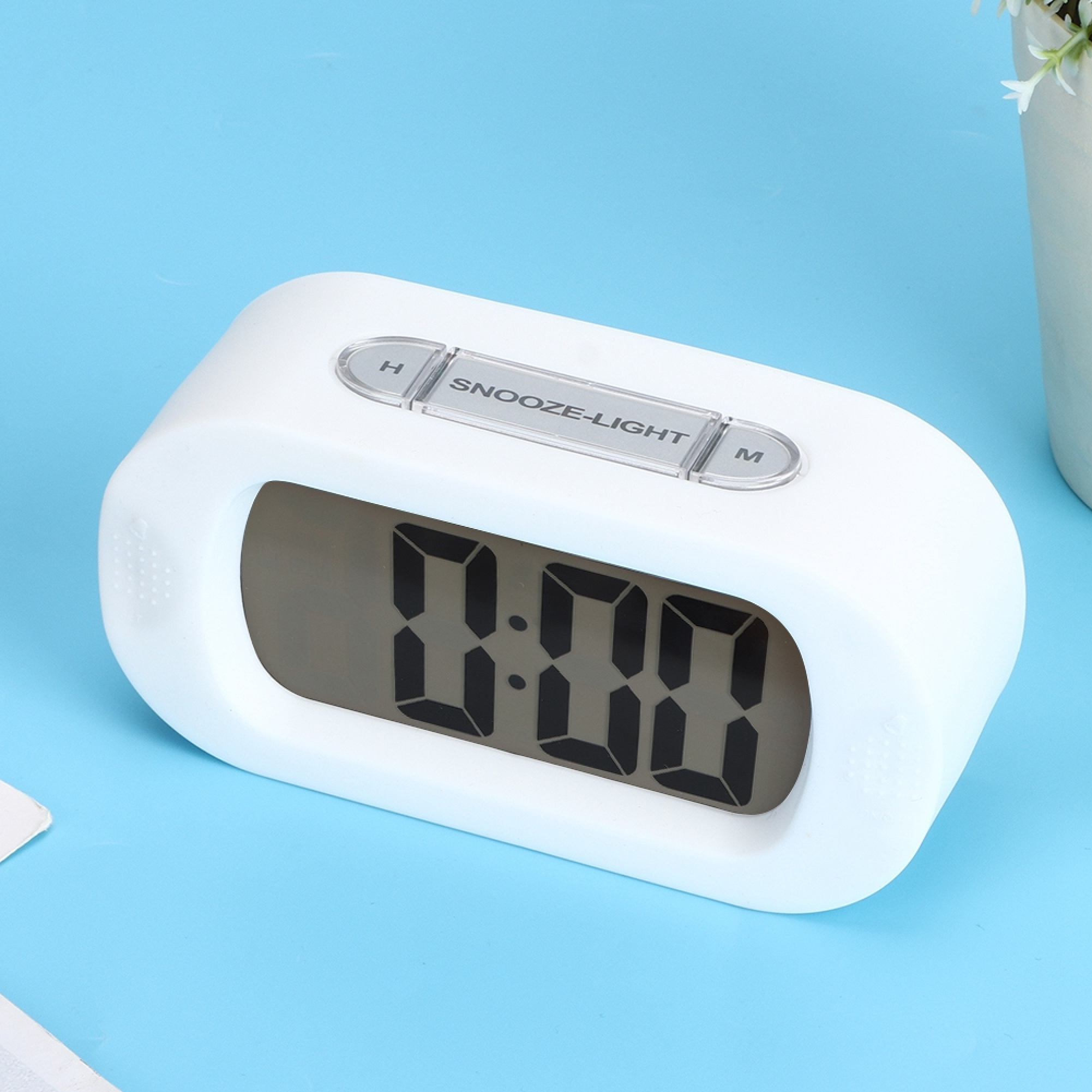 Ein weißer digitaler Wecker mit der Anzeige 0:00 auf blauem Hintergrund.