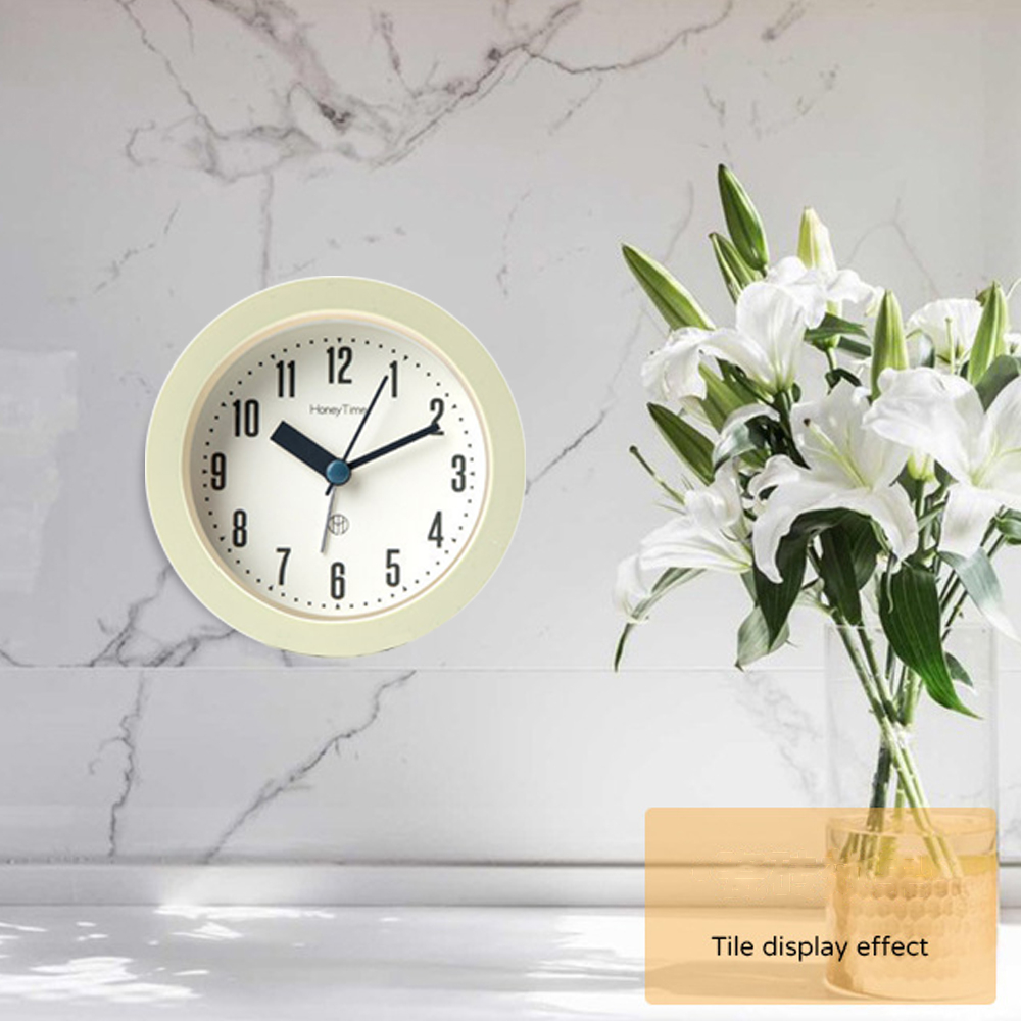 Eine Wanduhr mit cremefarbenem Rahmen neben einem Glas mit weißen Lilien.