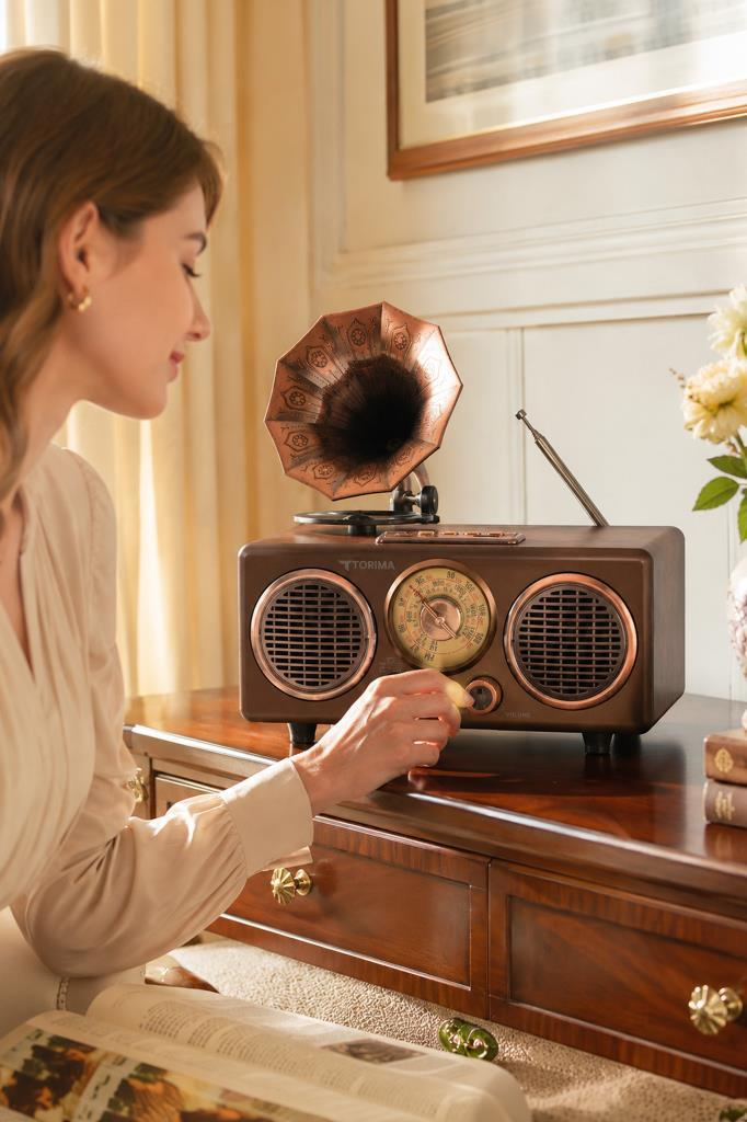 Bir kadın ahşap bir masada kahverengi, vintage radyo-plak çalari ayarlıyor.