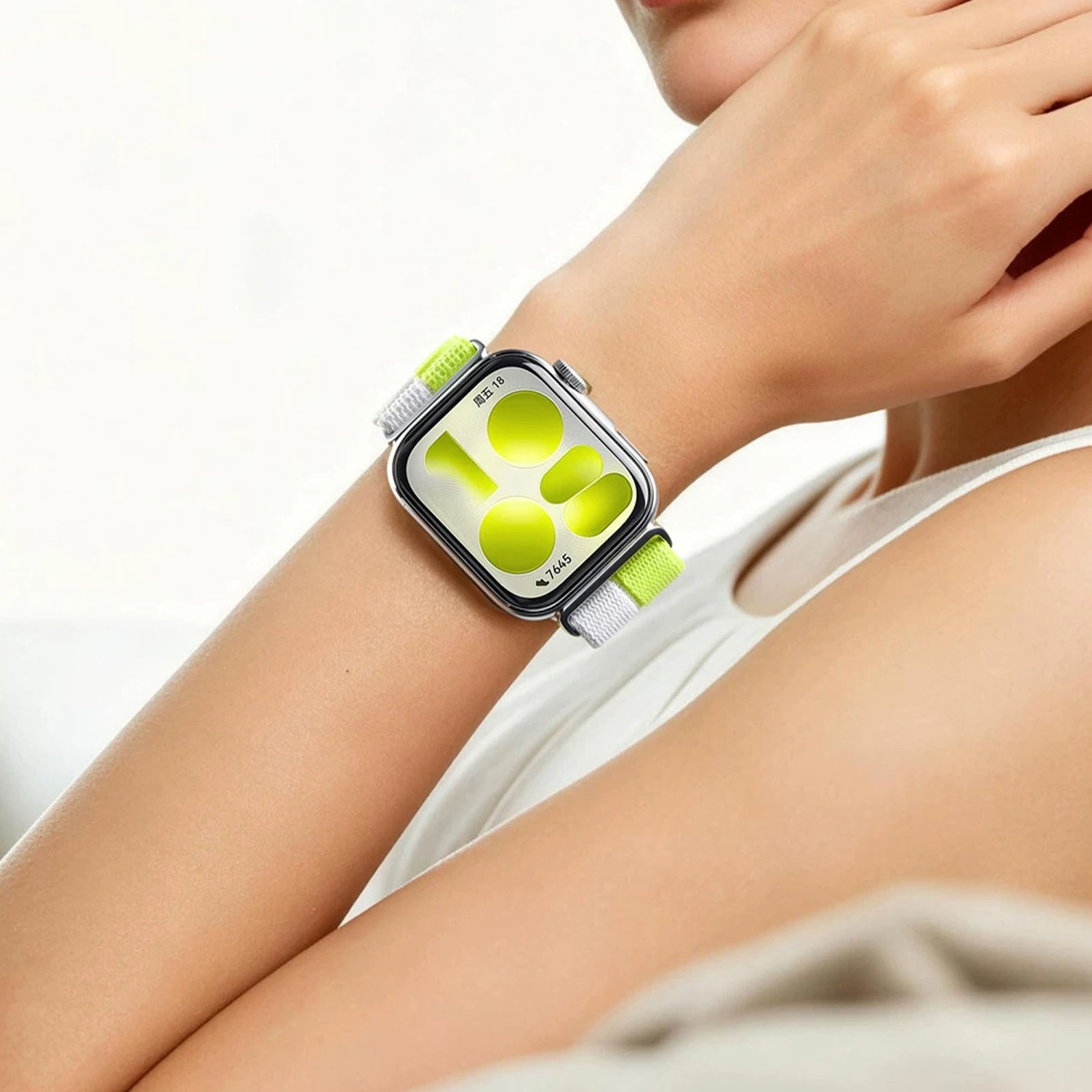Eine Frau trägt eine Smartwatch mit einem grünen und weißen Armband. Das Zifferblatt ist hellgrün.