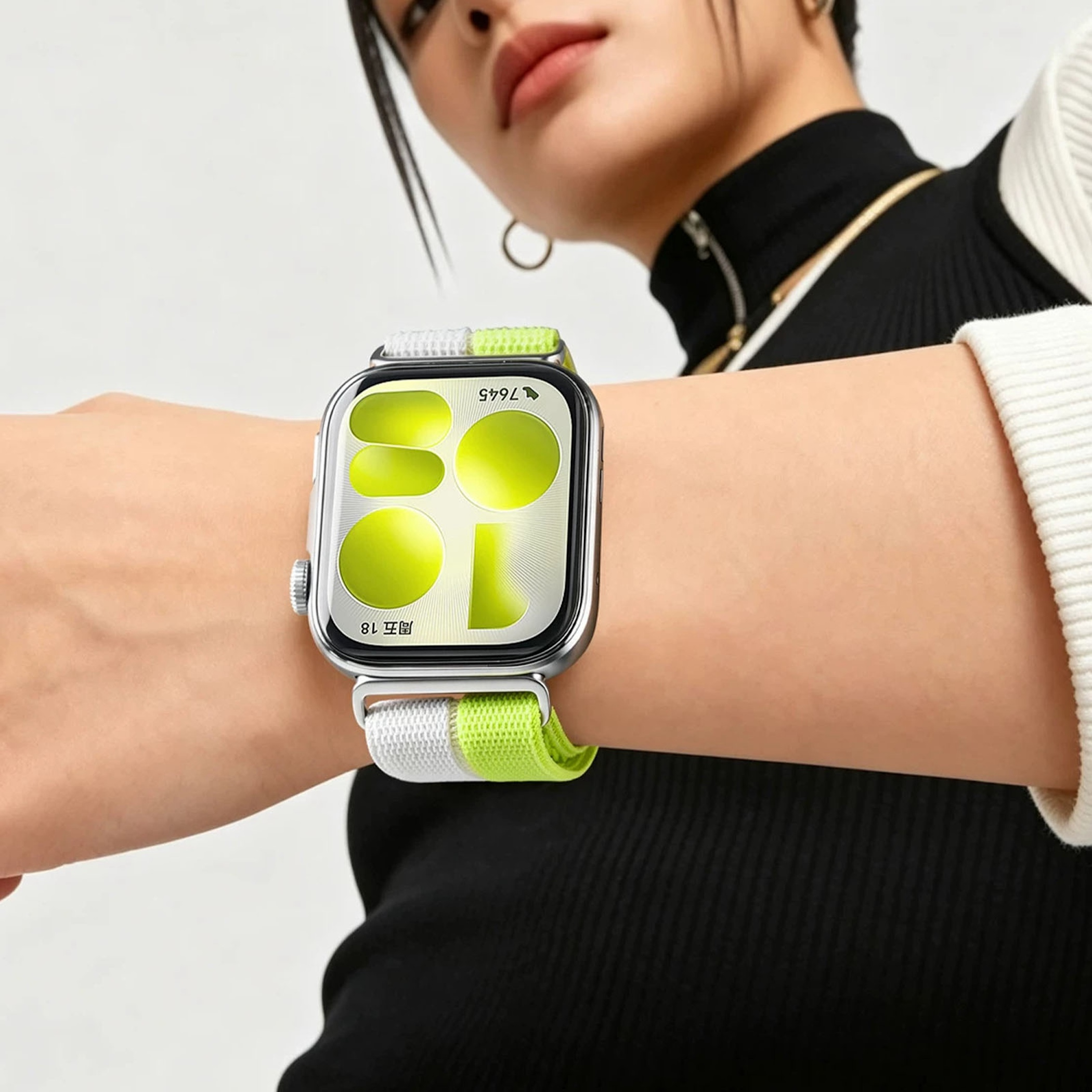 Eine Frau trägt eine Smartwatch mit grün-weißem Armband und leuchtend grünen Zifferblättern.