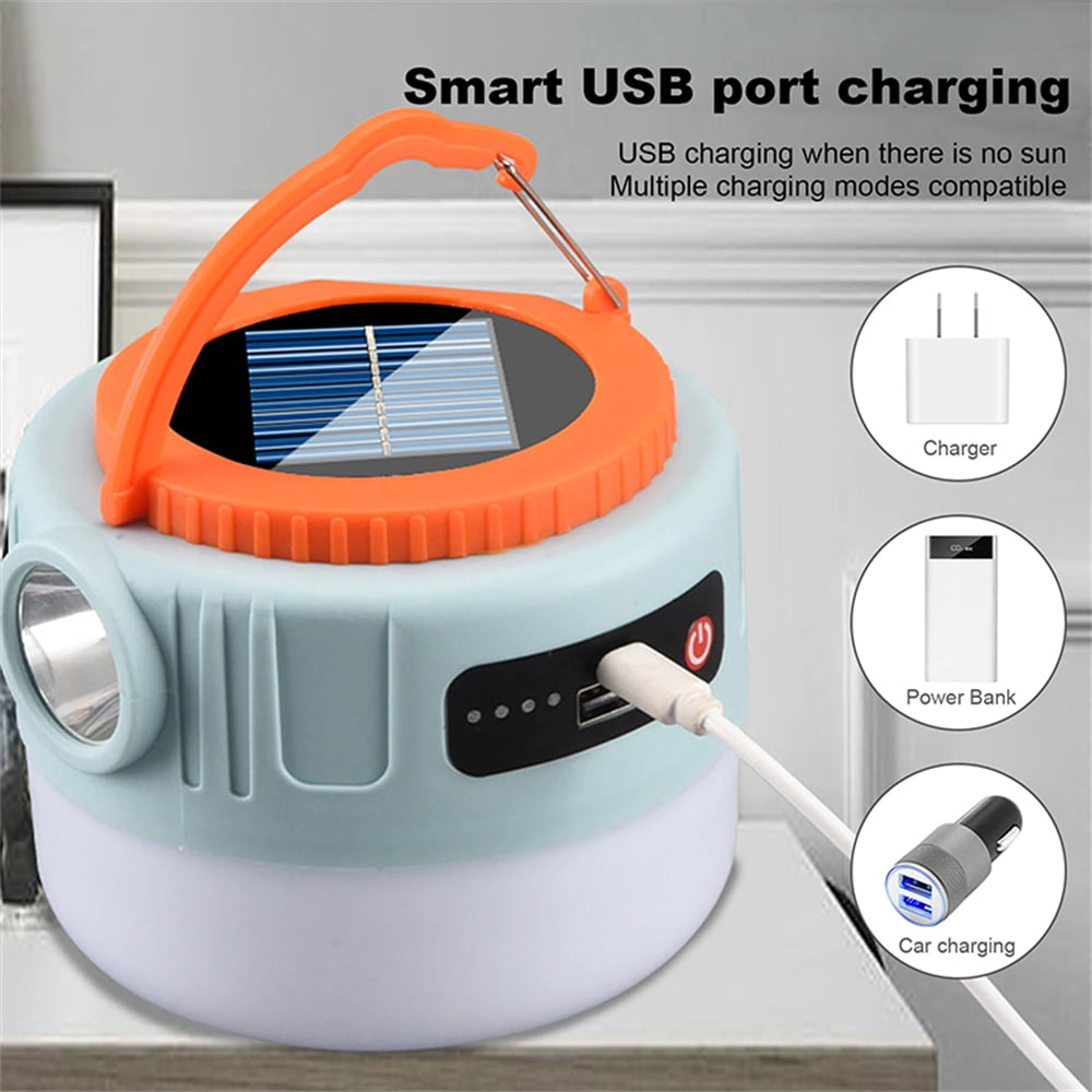 Eine hellblaue Laterne mit orangefarbenem Griff und Solarpanel lädt per USB.