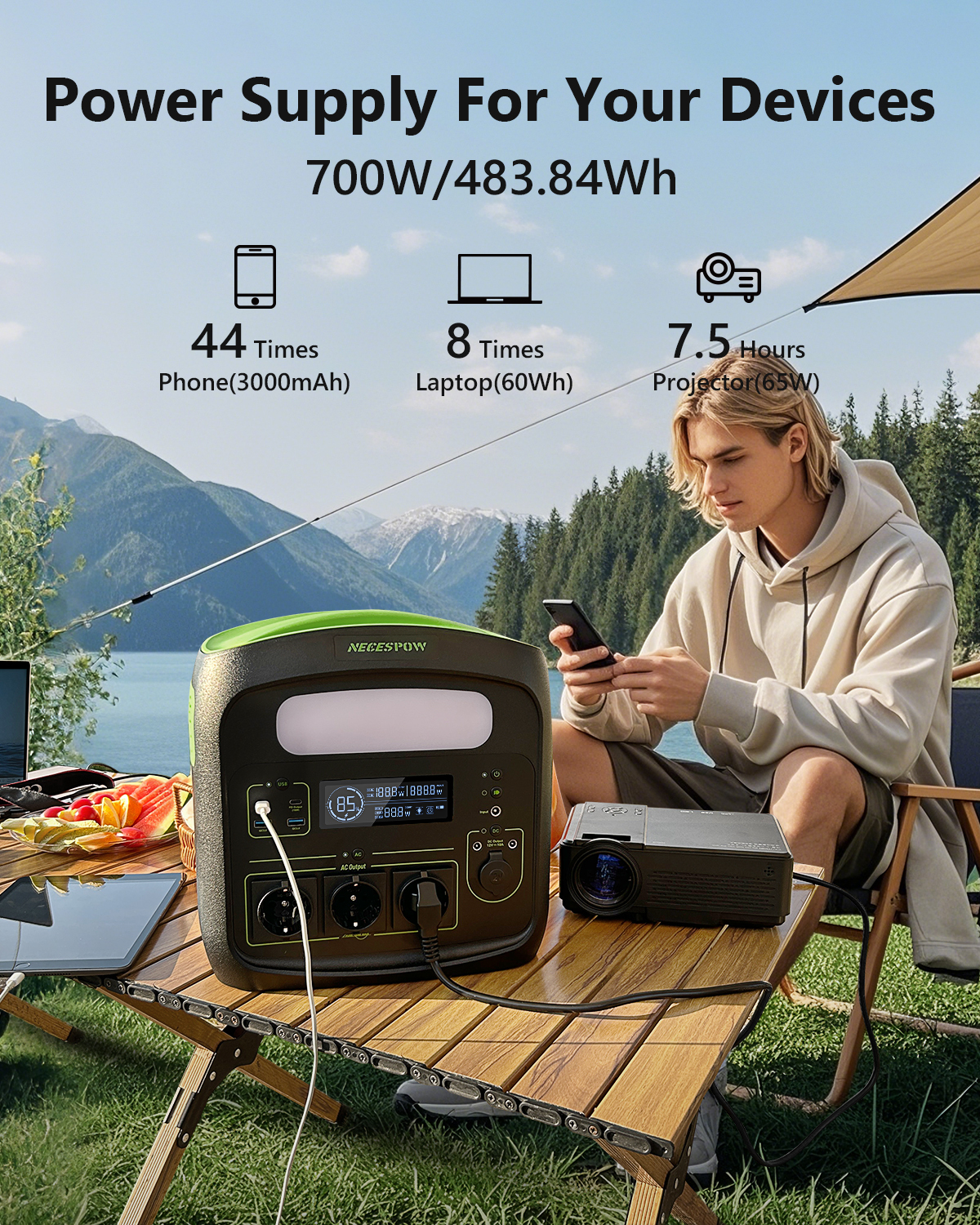 Estación de energía portátil con proyector y hombre en mesa al aire libre con fondo de montaña.