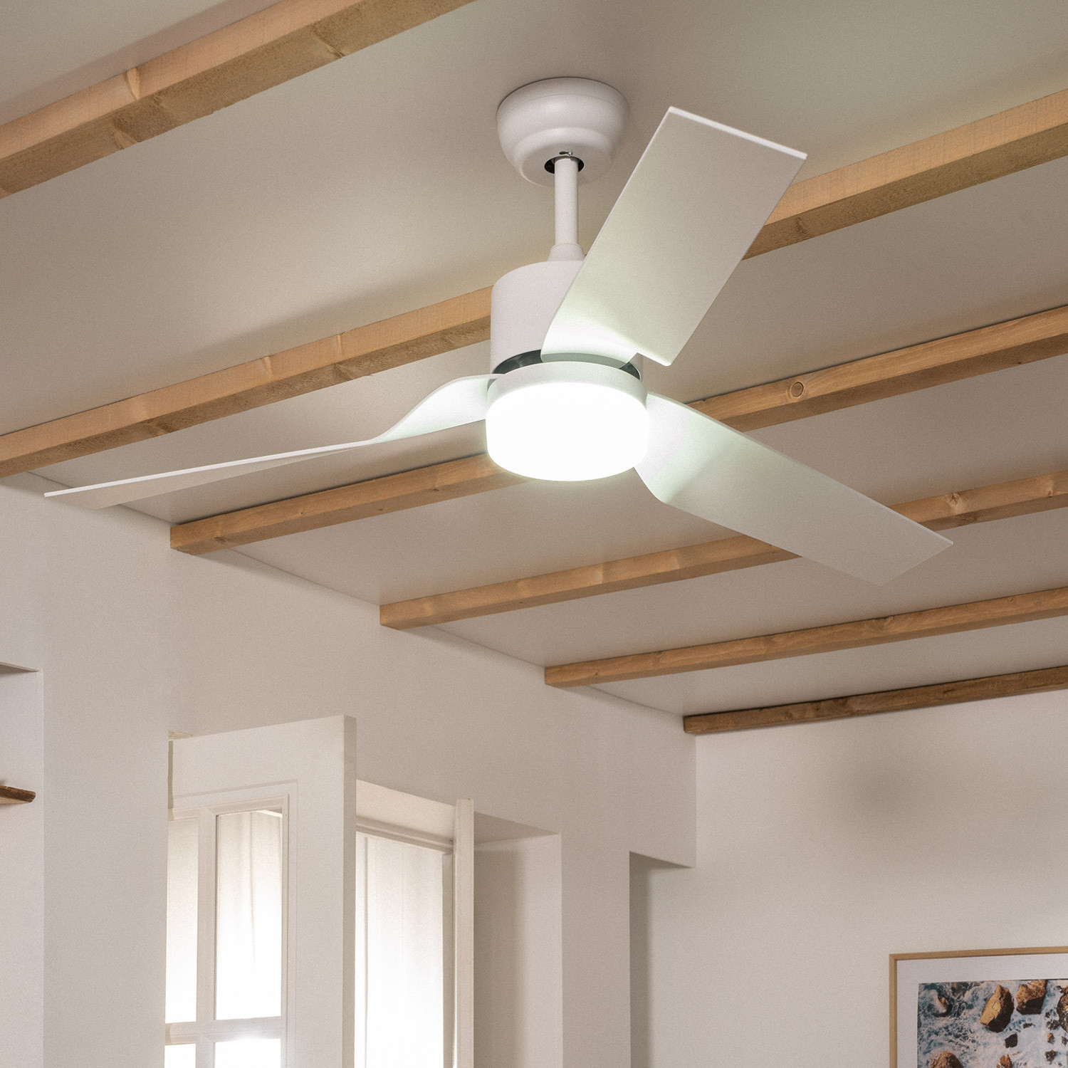 Un ventilatore da soffitto bianco con luce è montato su un soffitto con travi in legno.