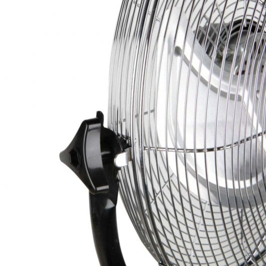 Primer plano de un ventilador plateado con mango negro sobre fondo blanco.