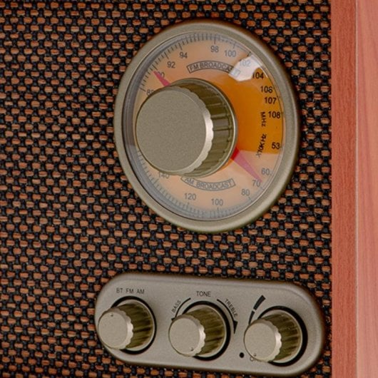 Primo piano di una radio con quadrante di frequenza e manopole su griglia marrone.