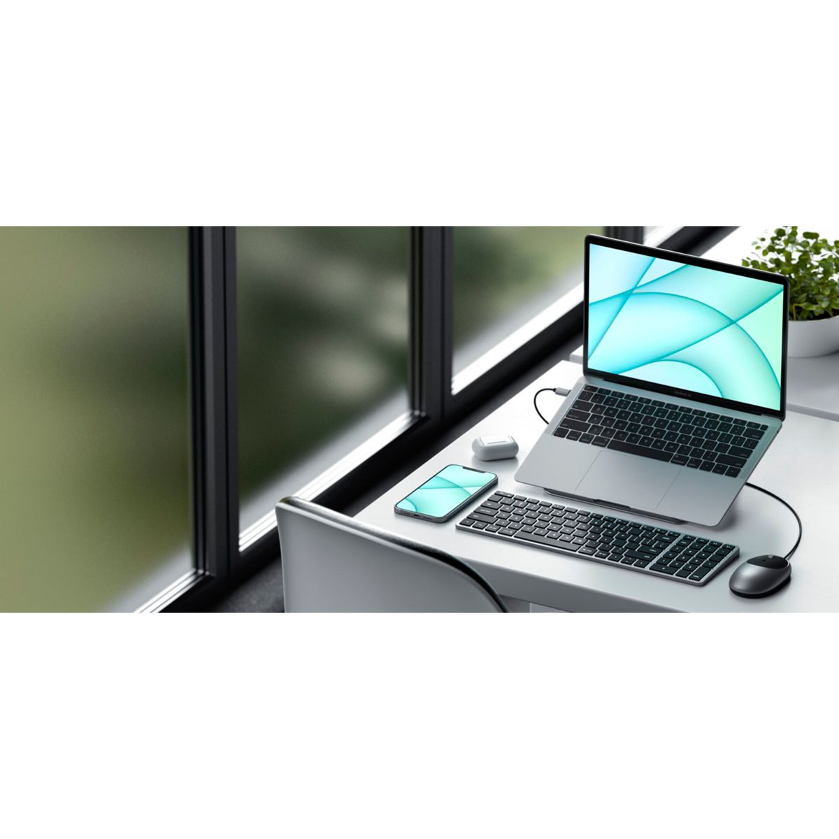 Ein Laptop, Smartphone, Tastatur und Maus auf einem Schreibtisch neben einem Fenster.