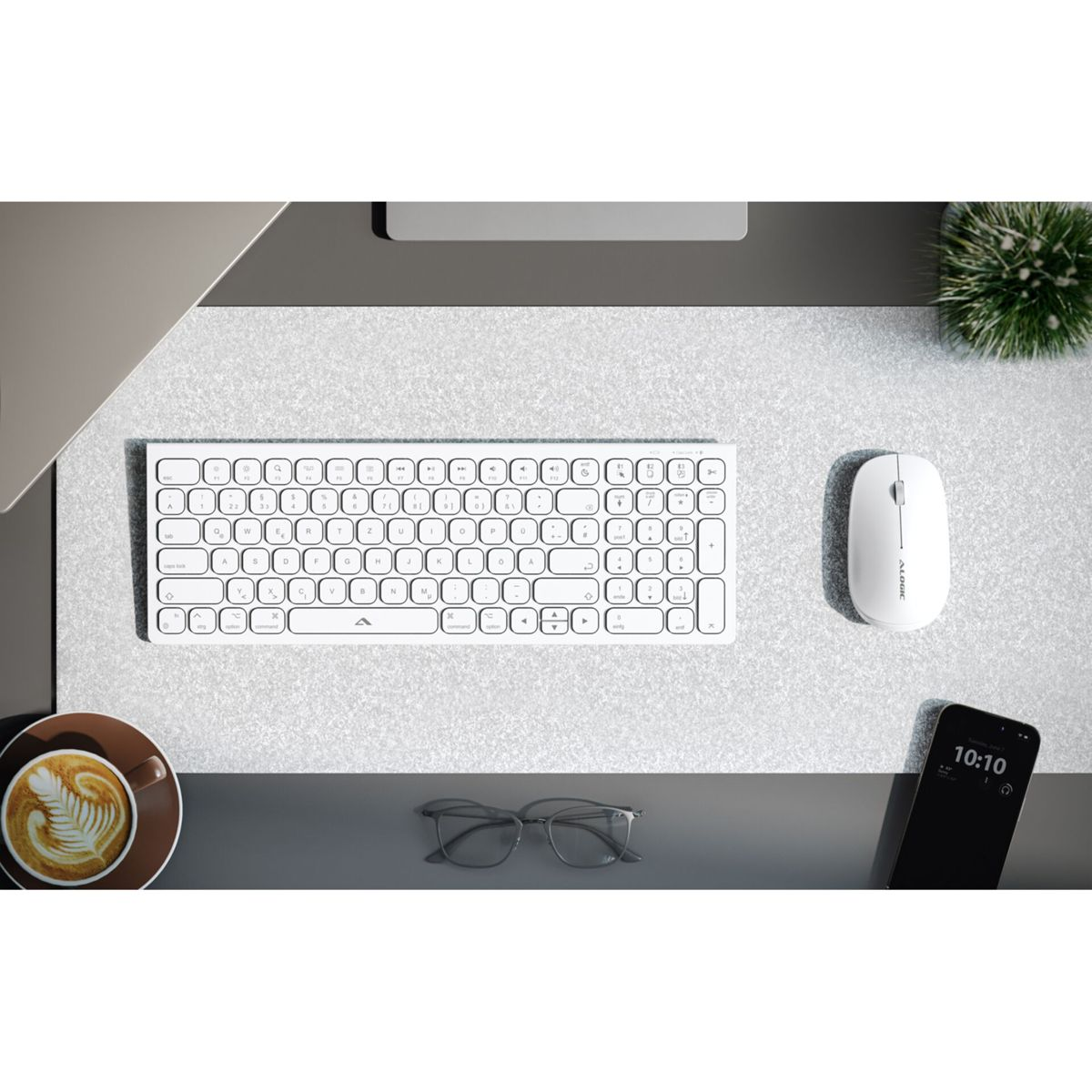 Ein weißes Keyboard, eine Maus, eine Kaffeetasse und eine Brille auf einem Schreibtisch.