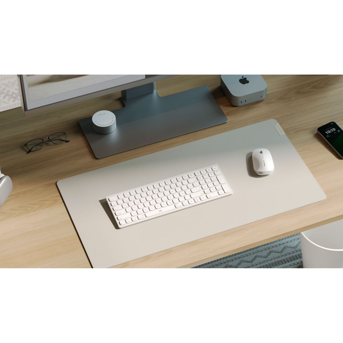 Ein weißes Keyboard und eine Maus liegen auf einer hellgrauen Matte auf einem Holztisch.