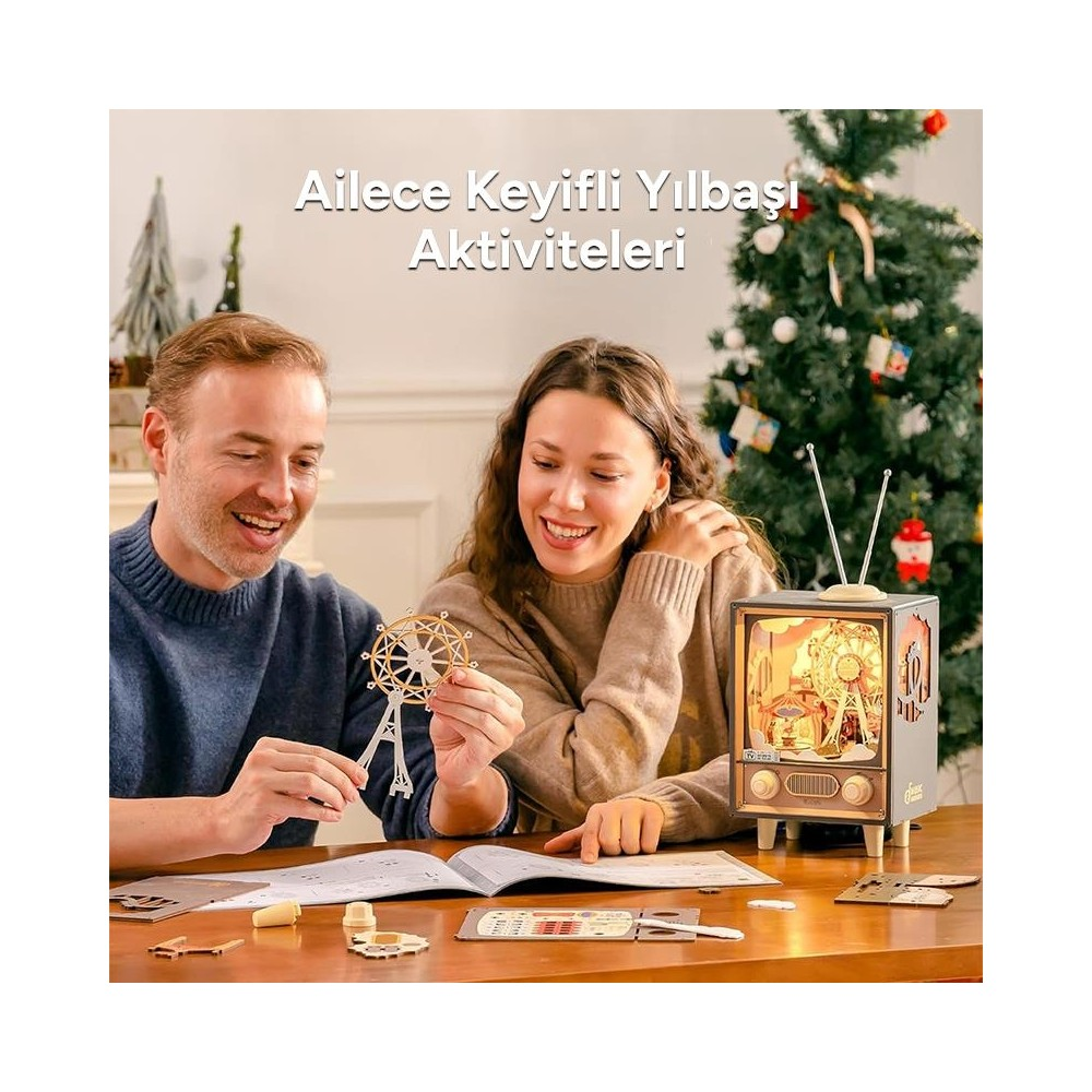Bir çift, Noel ağacı ve aydınlatılmış model TV önünde ahşap dönme dolap modeli yapıyor.