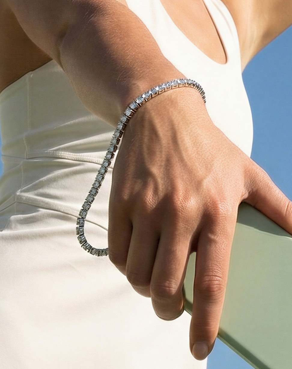 Eine Hand mit einem Diamantarmband vor einem blauen Himmel.