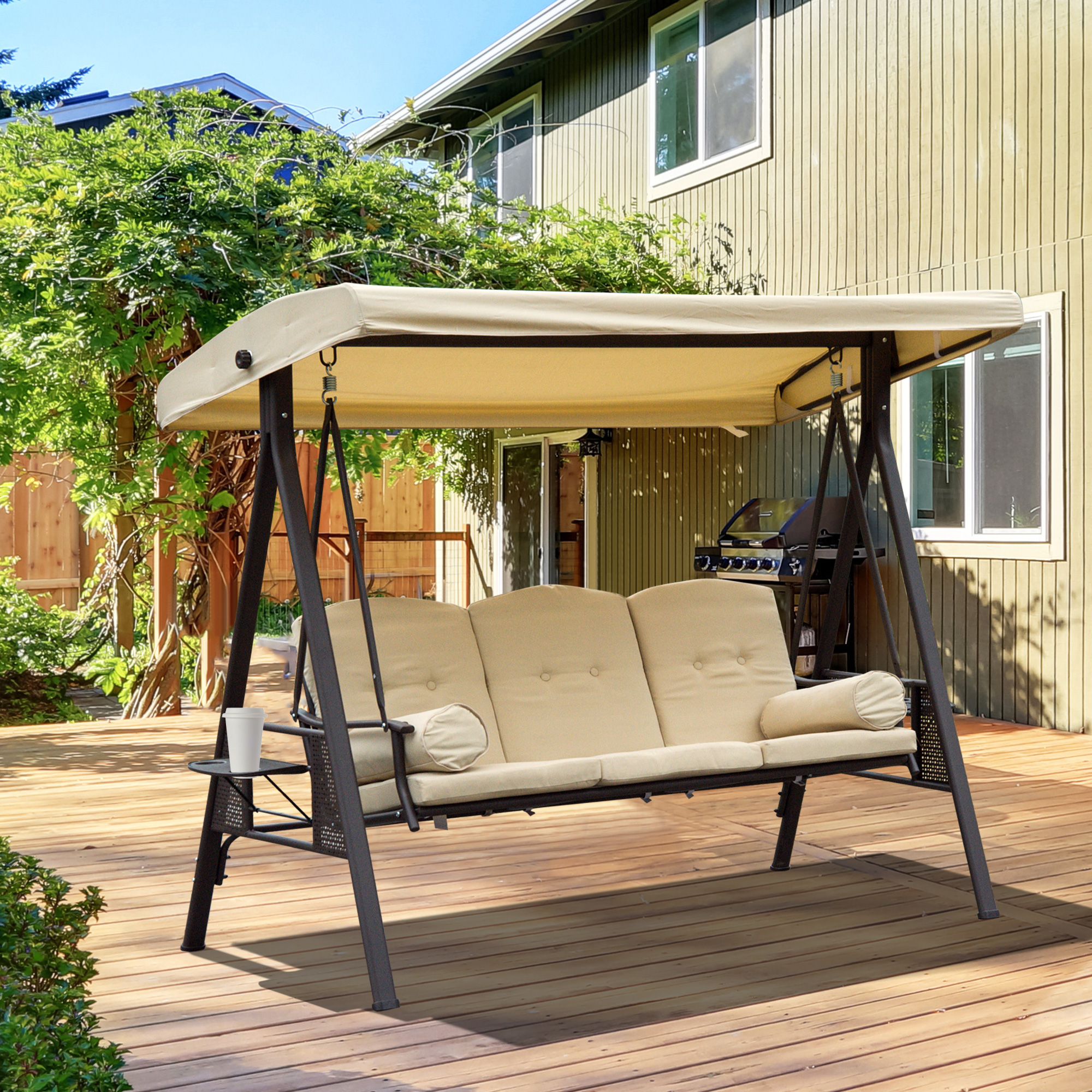 Un'altalena da portico beige con tenda su un ponte di legno con grill sullo sfondo.
