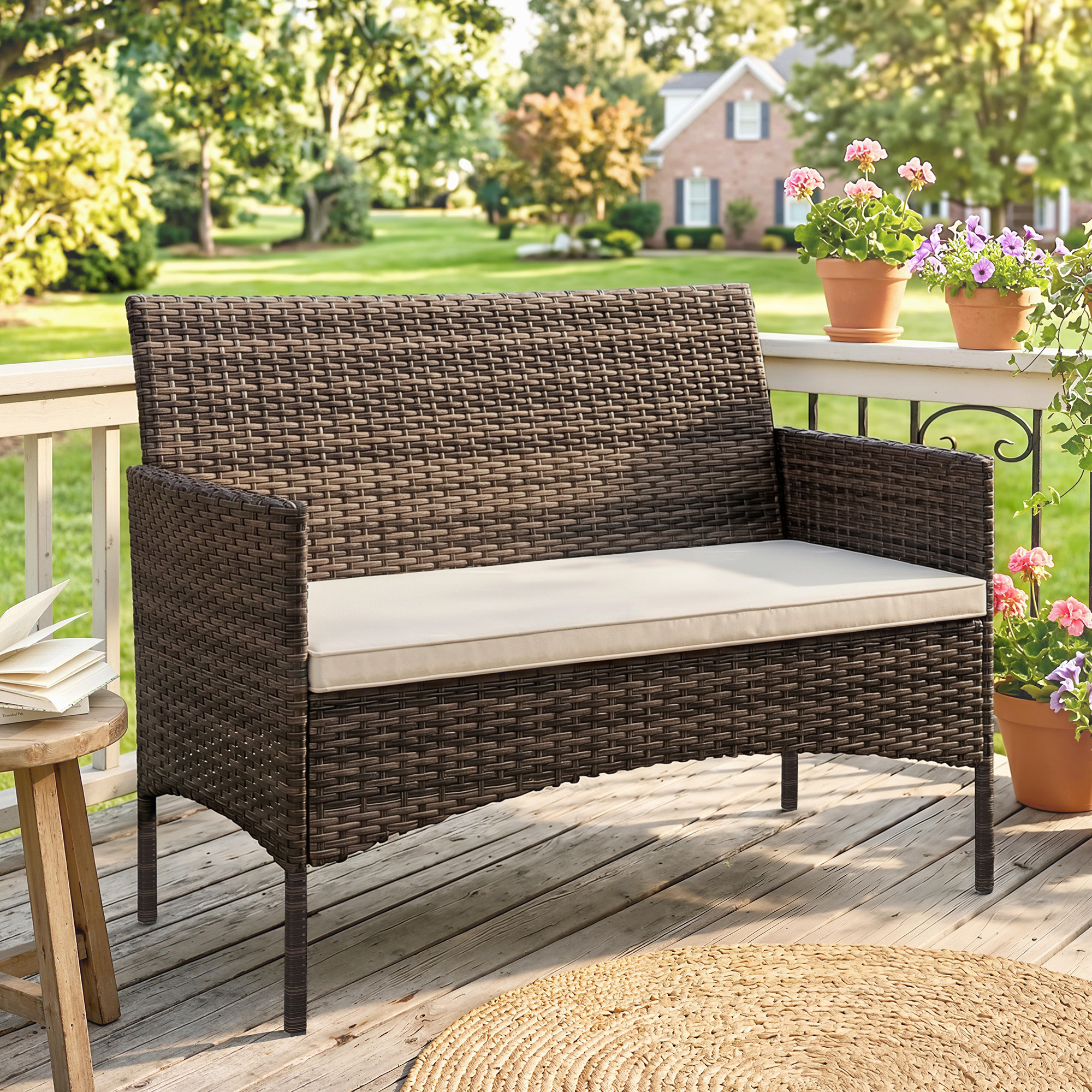Una panchina da giardino in rattan marrone con cuscino color crema su un portico in legno.