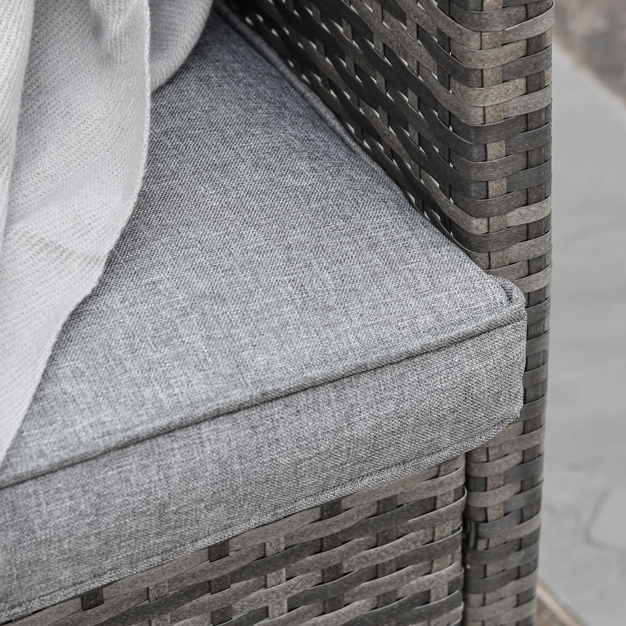 Cuscino grigio con coperta su sedia in rattan.