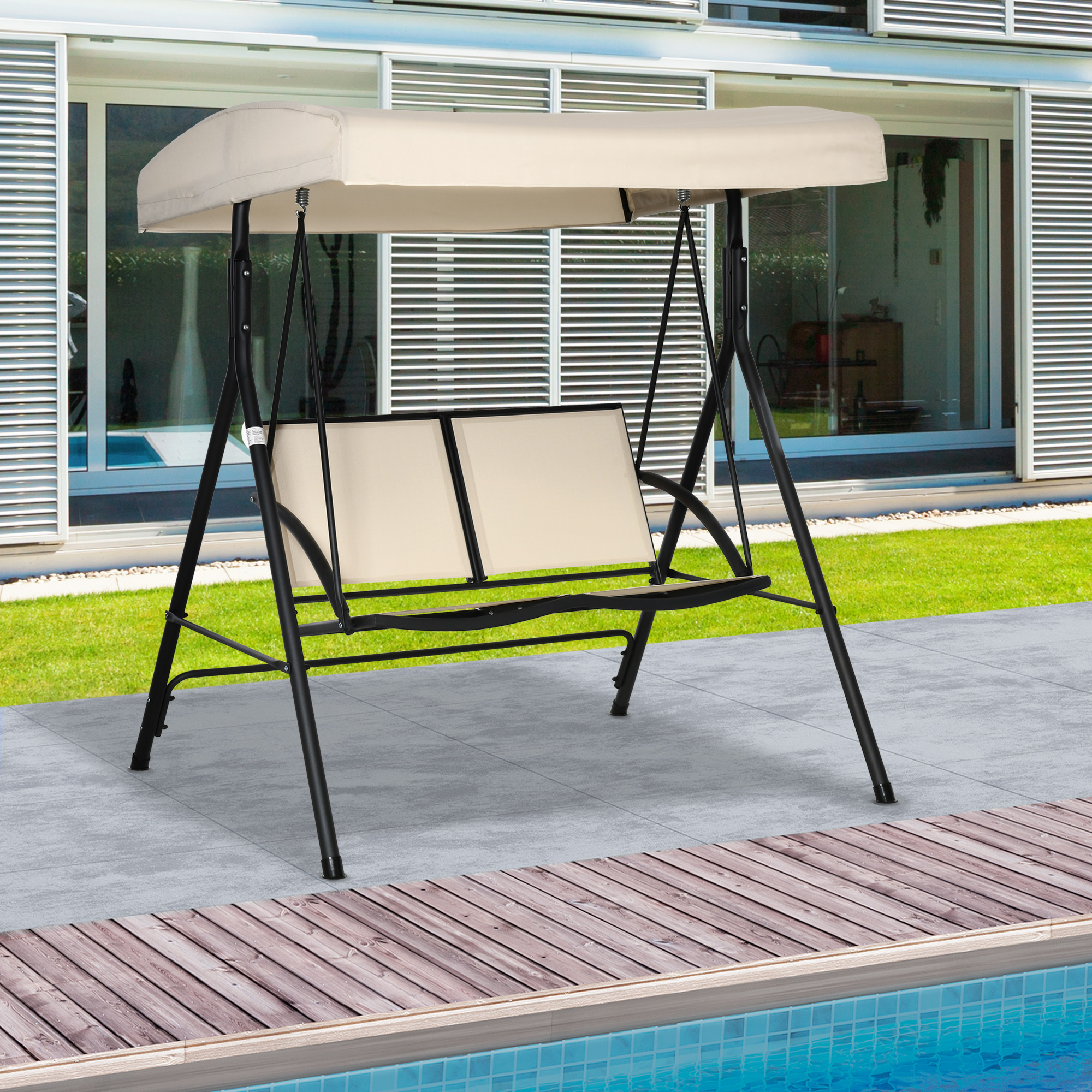 Una seduta a dondolo beige con telaio in metallo nero si trova su un patio in pietra accanto a una piscina.