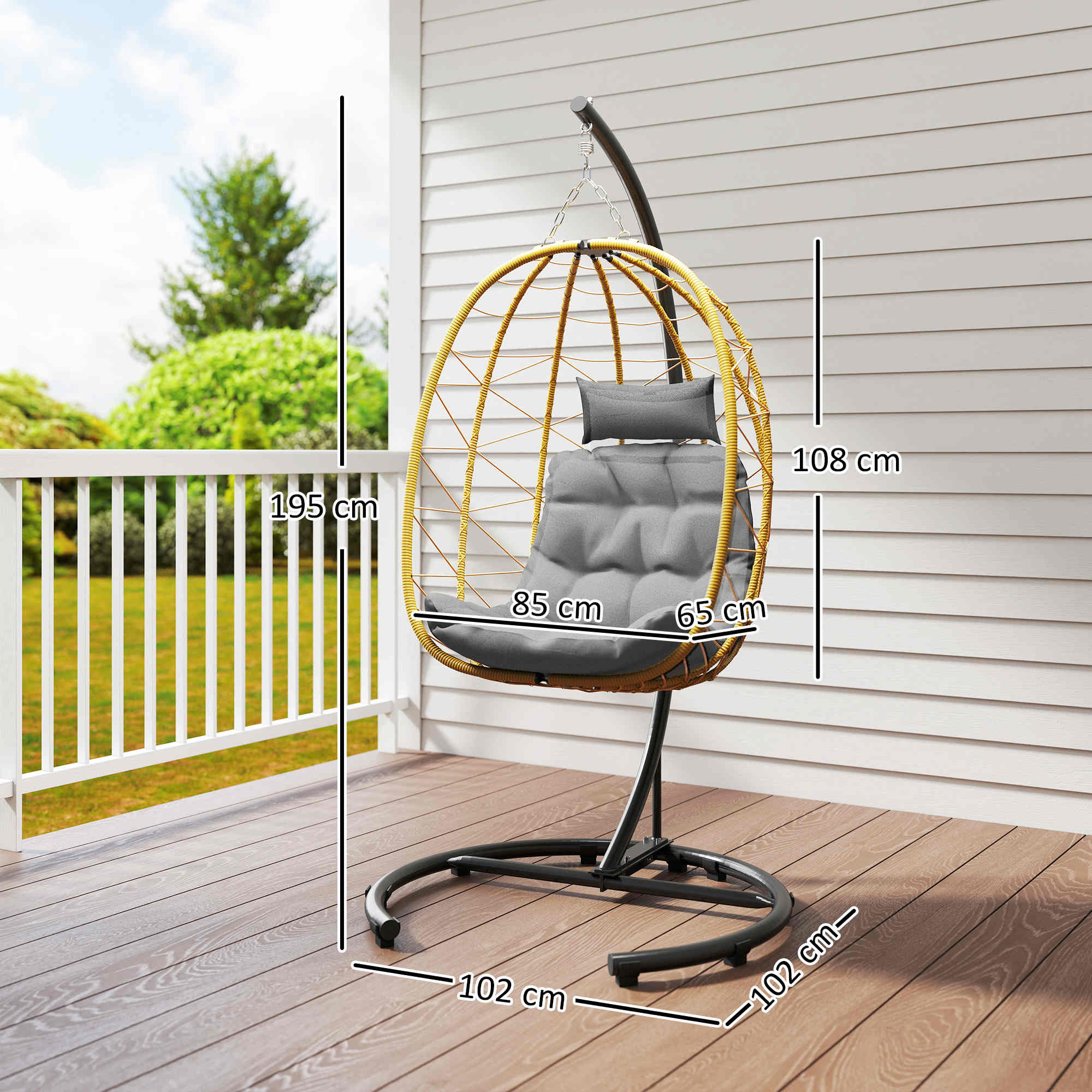 Una sedia sospesa in rattan a forma di uovo con cuscini grigi su un ponte di legno.