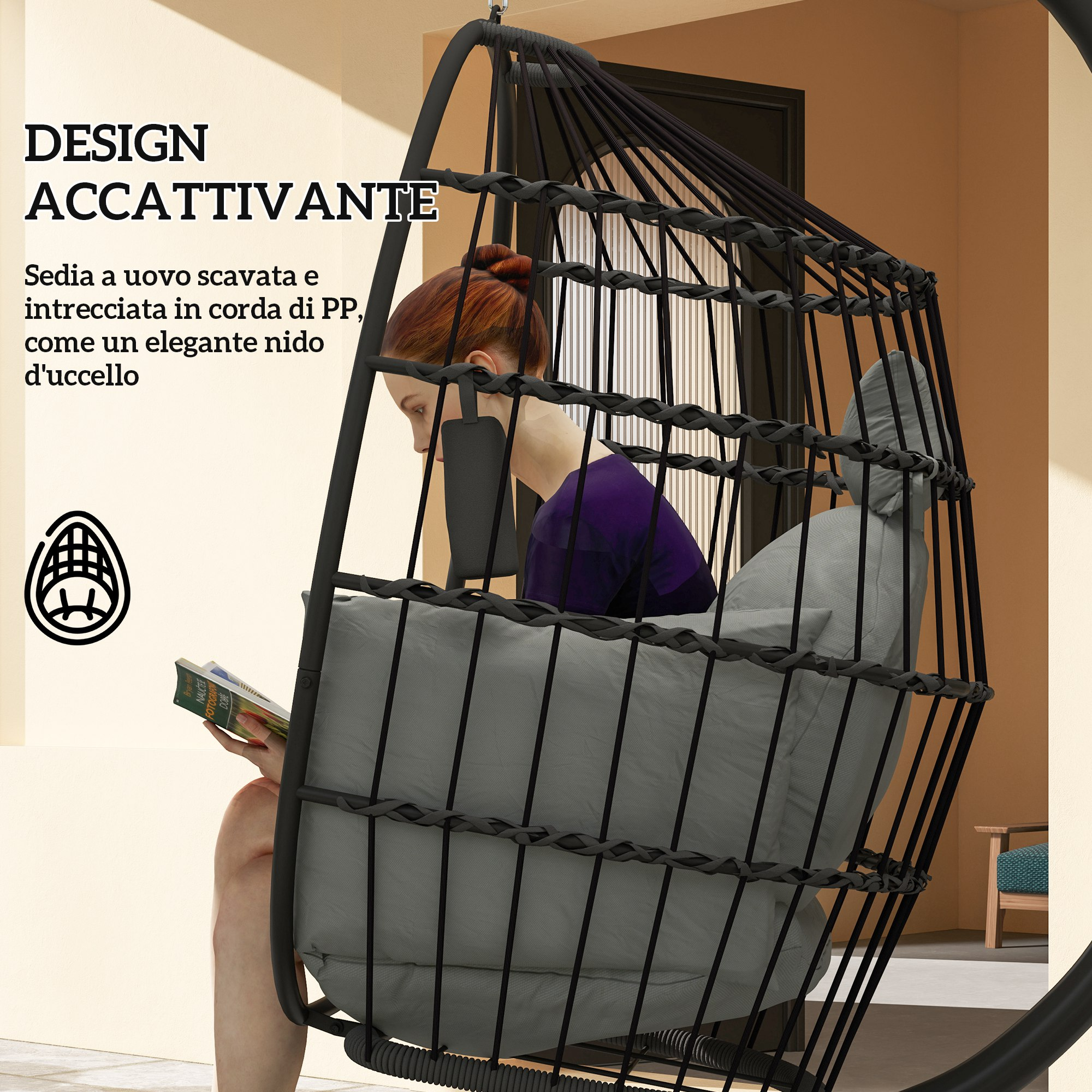 Una donna legge un libro su una sedia sospesa nera con cuscini grigi.