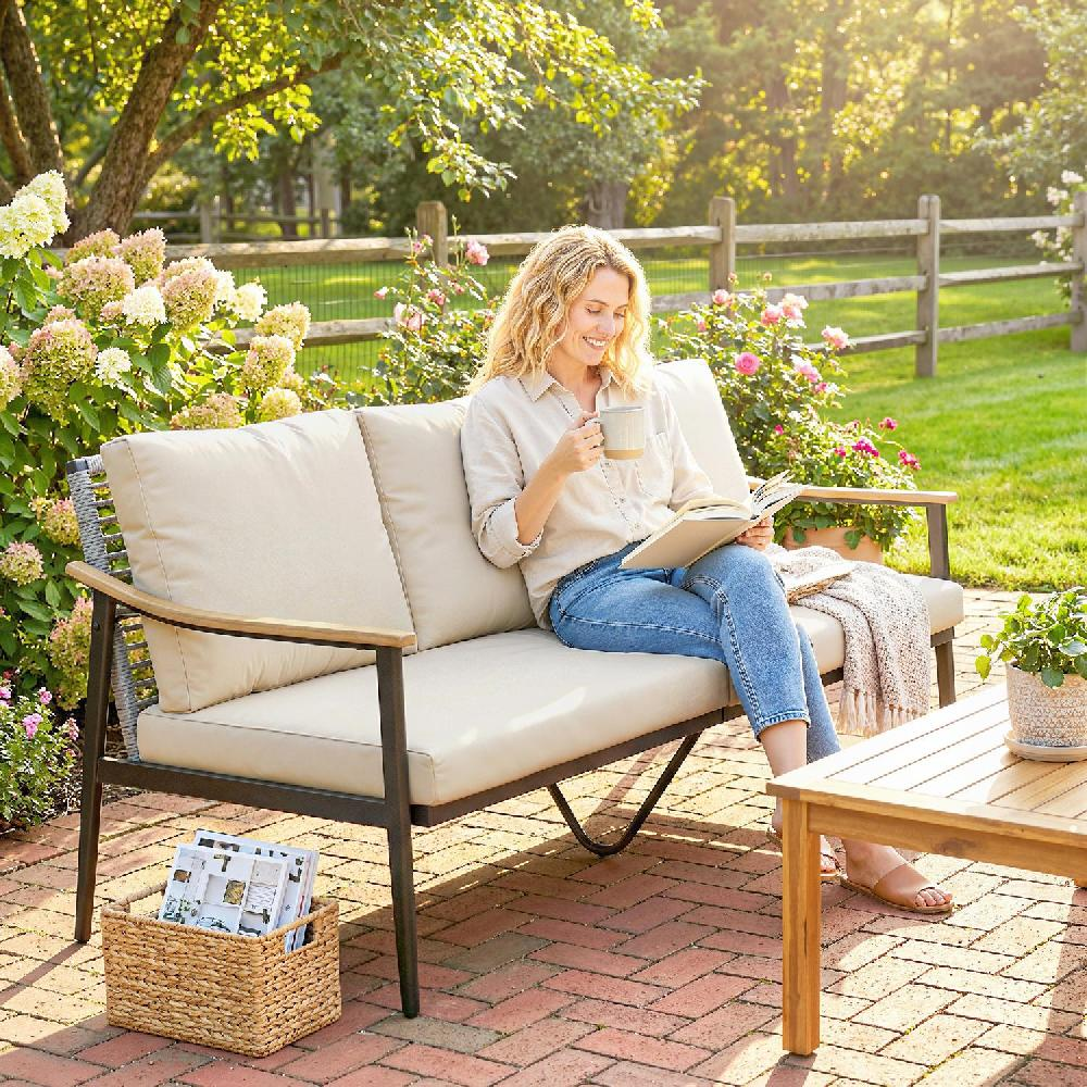 Donna legge libro su divano in giardino con tazza caffè.