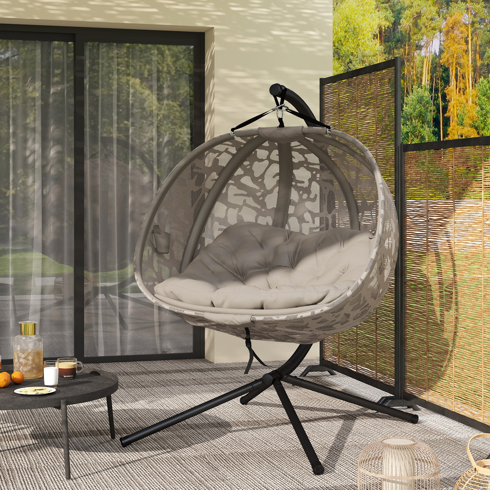 Una moderna sedia sospesa a forma di uovo con cuscini su un patio con tavolo e bevande.