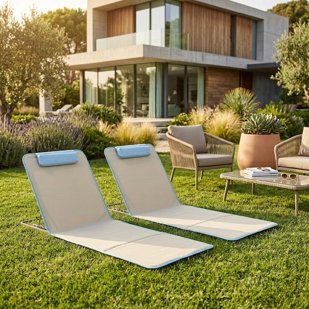 Due lettini da spiaggia sull'erba davanti a una casa moderna con mobili da esterno.