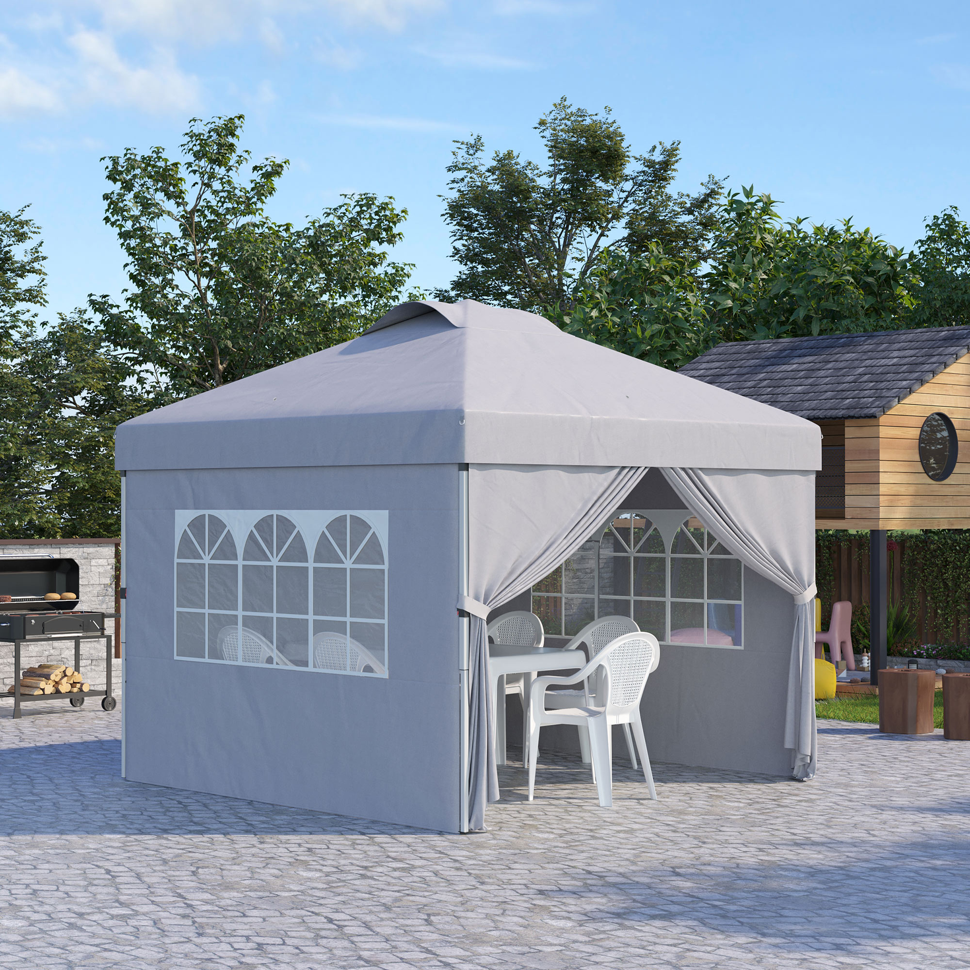 Una tenda gazebo grigia con tavolo e sedie, accanto a un barbecue e una casa sull'albero.