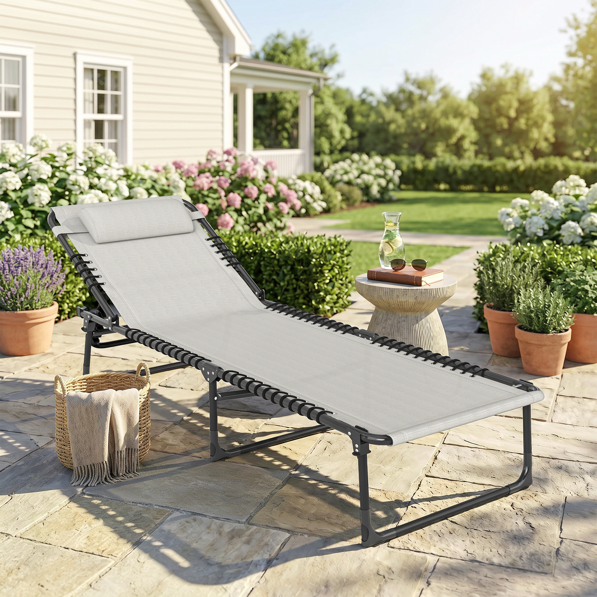 Una sedia a sdraio grigia su un patio di pietra con cesto e coperta.