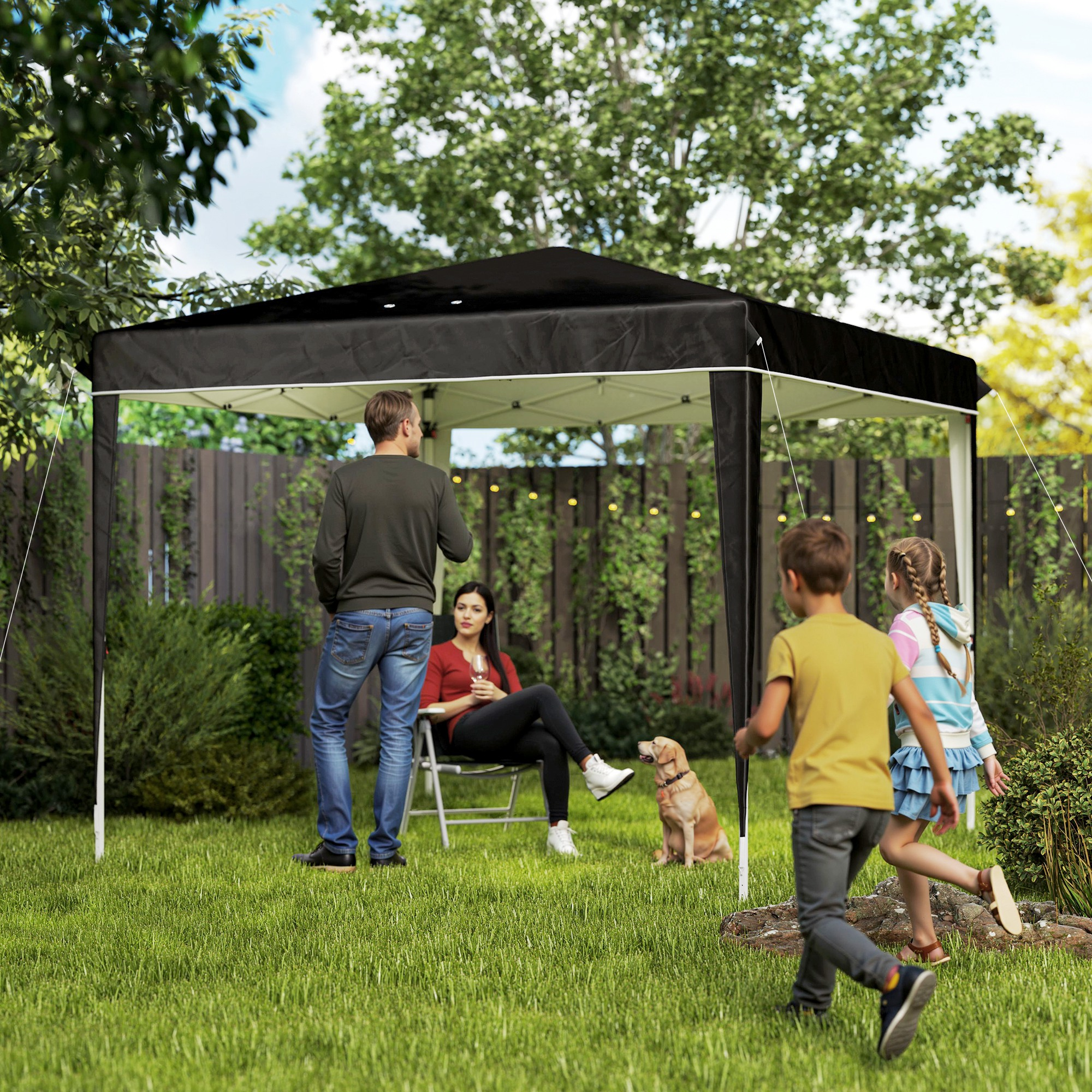 Famiglia con cane in giardino sotto un gazebo nero.