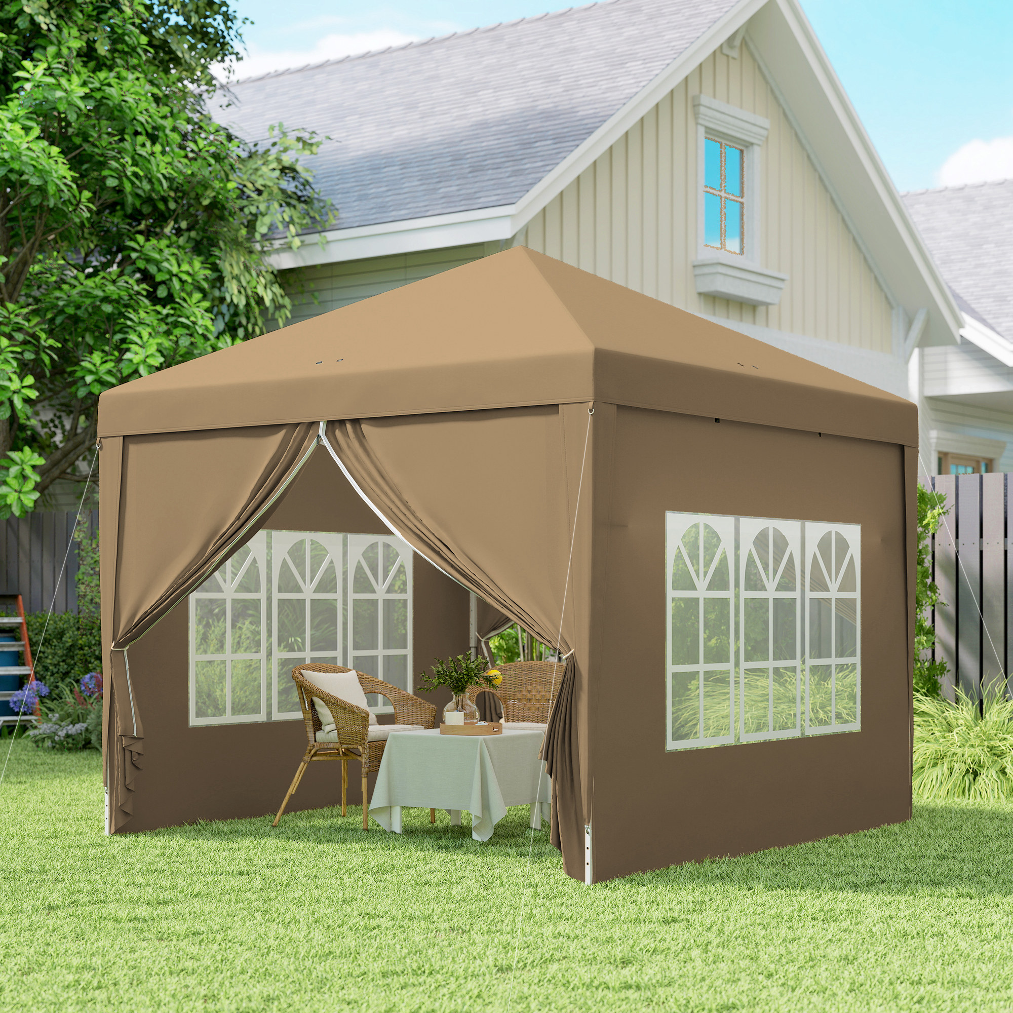 Una gazebo marrone con tavolo e sedie si trova sull'erba verde davanti a una casa.