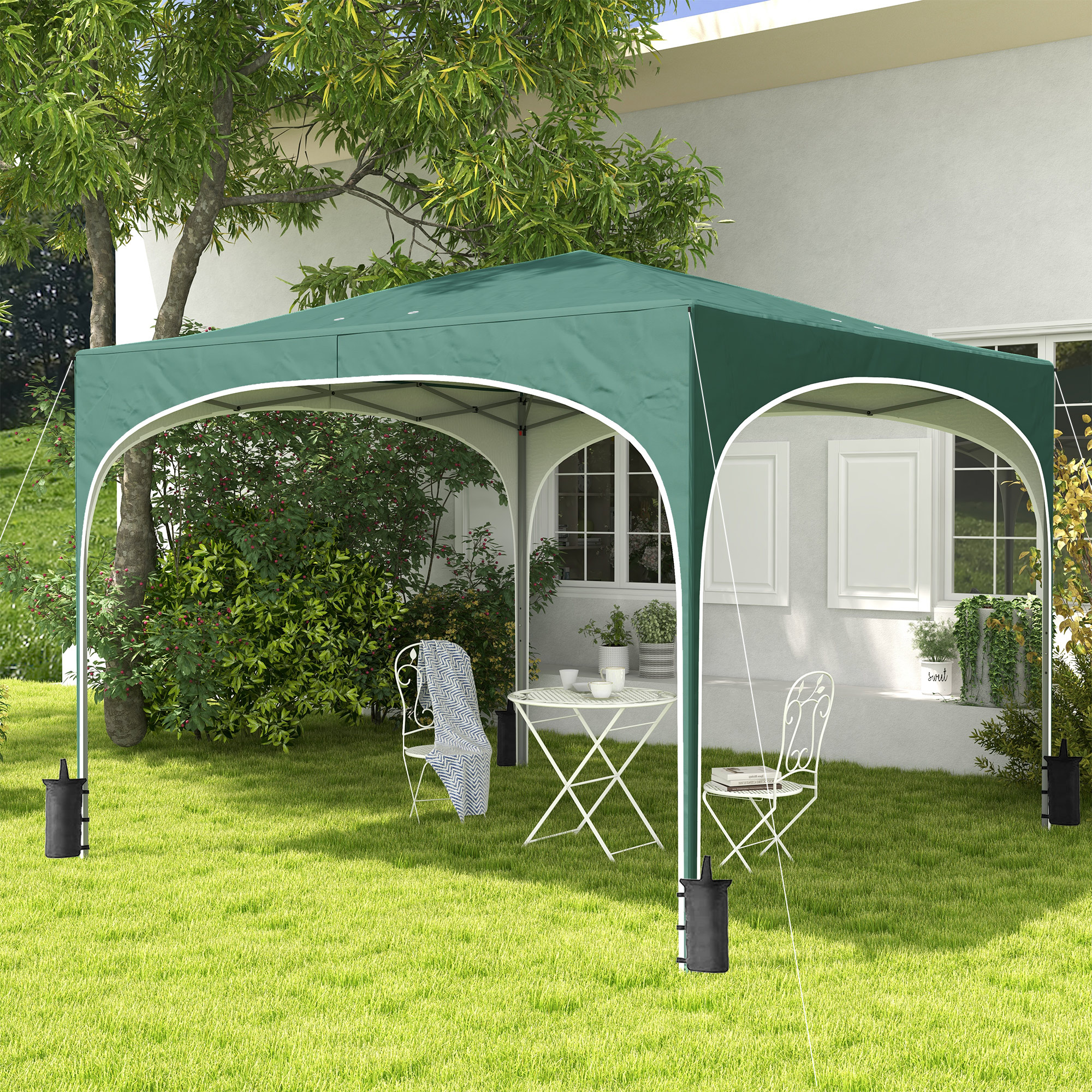 Una tenda verde si erge su un prato con tavolo e due sedie.