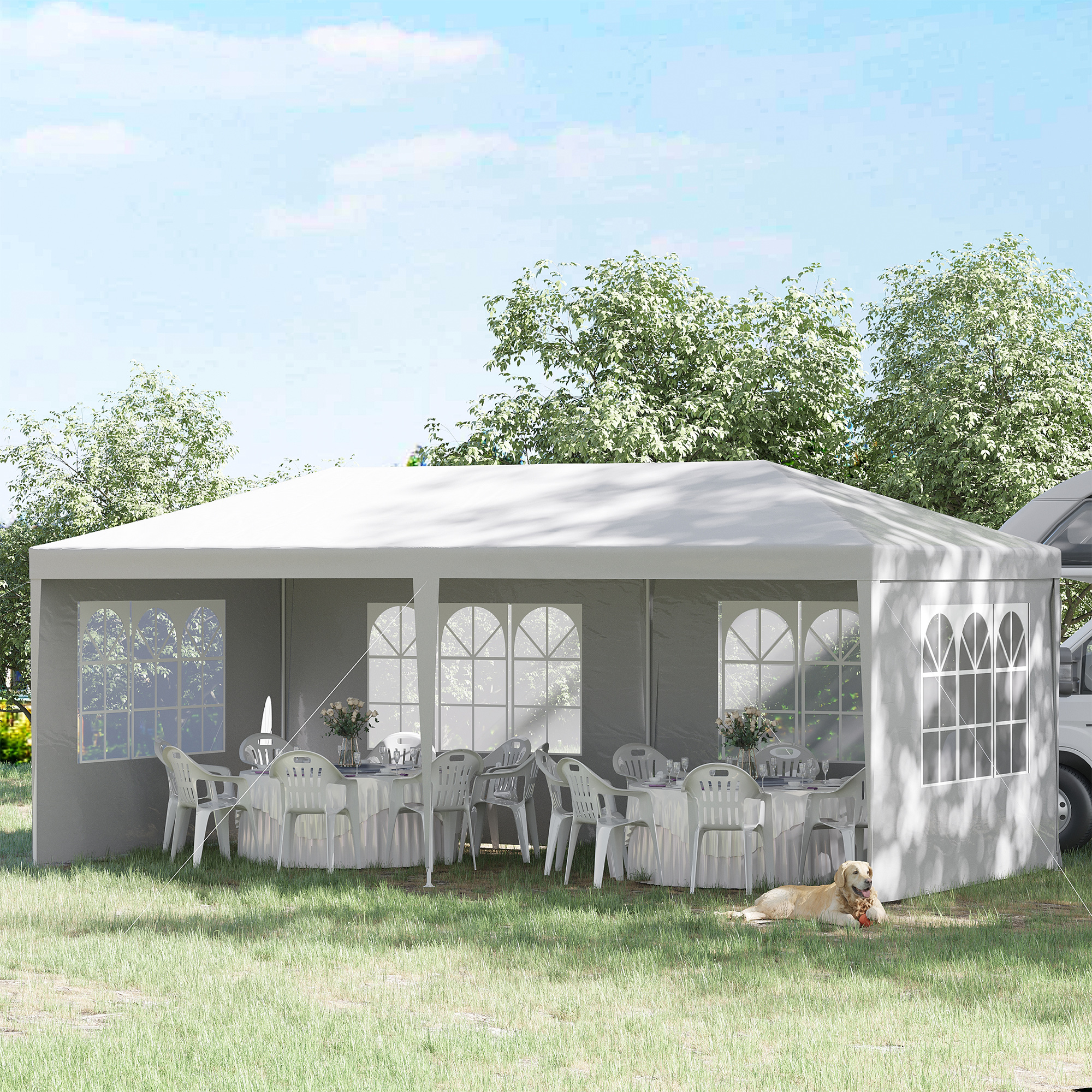 Una tenda bianca con tavoli e sedie è allestita sull'erba. Un cane giace davanti.