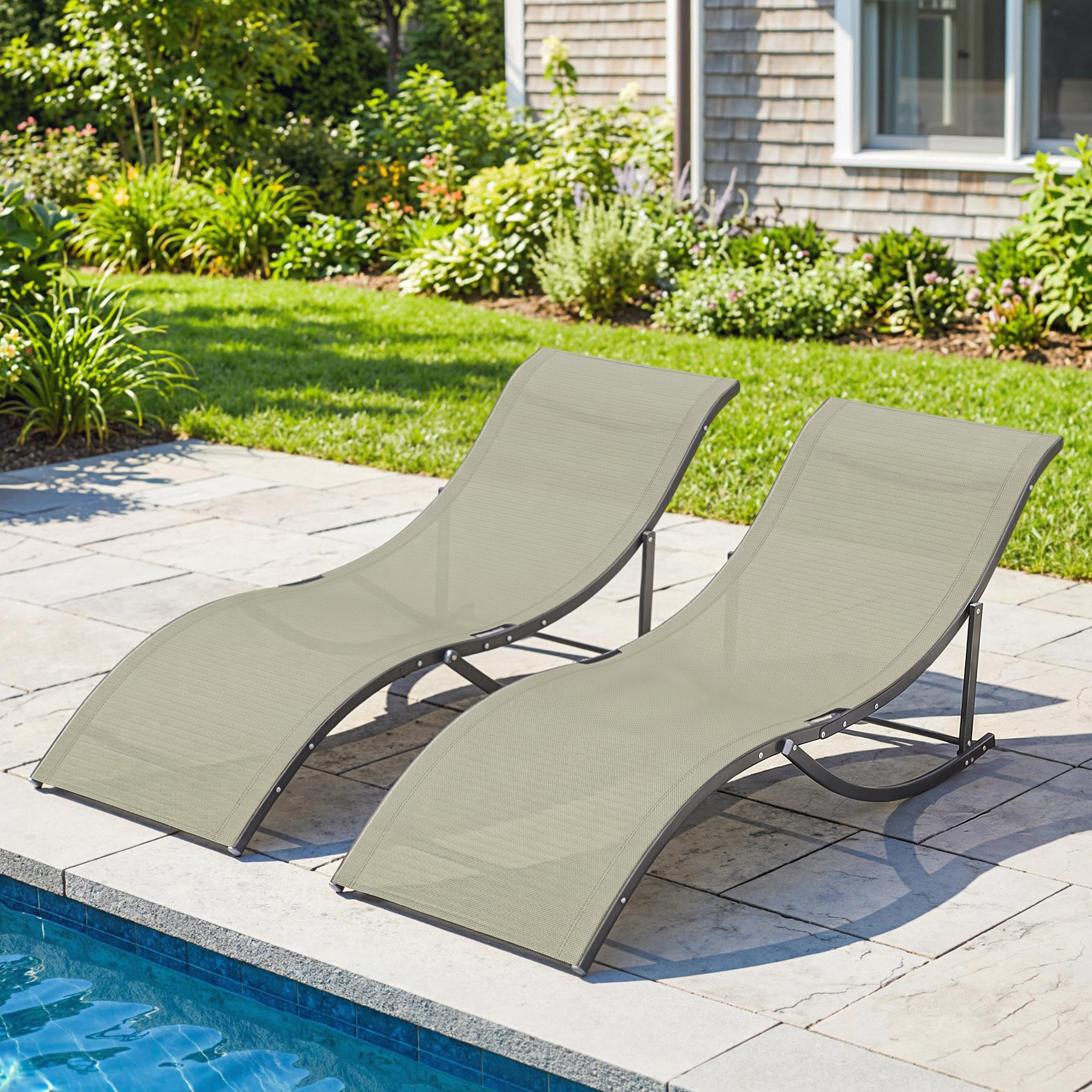 Due lettini prendisole beige su un patio di pietra vicino a una piscina.