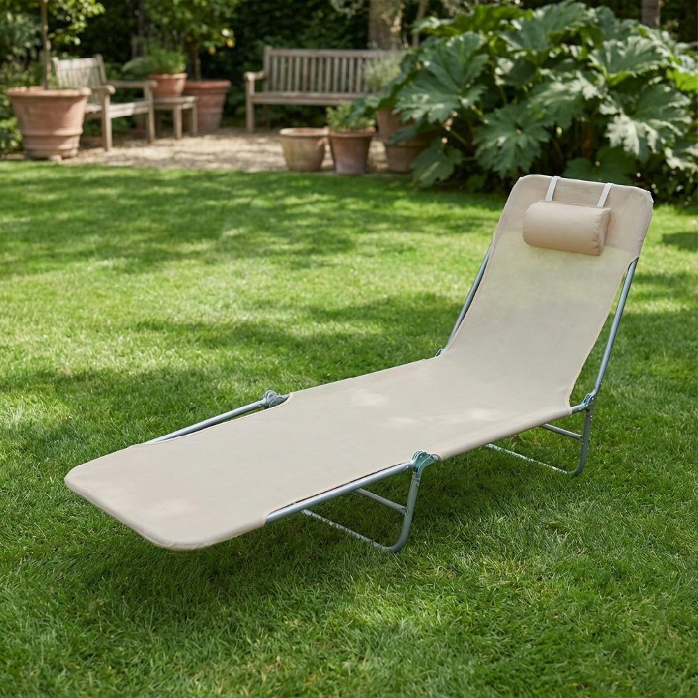 Una chaise longue beige con telaio in metallo poggia sull'erba verde.