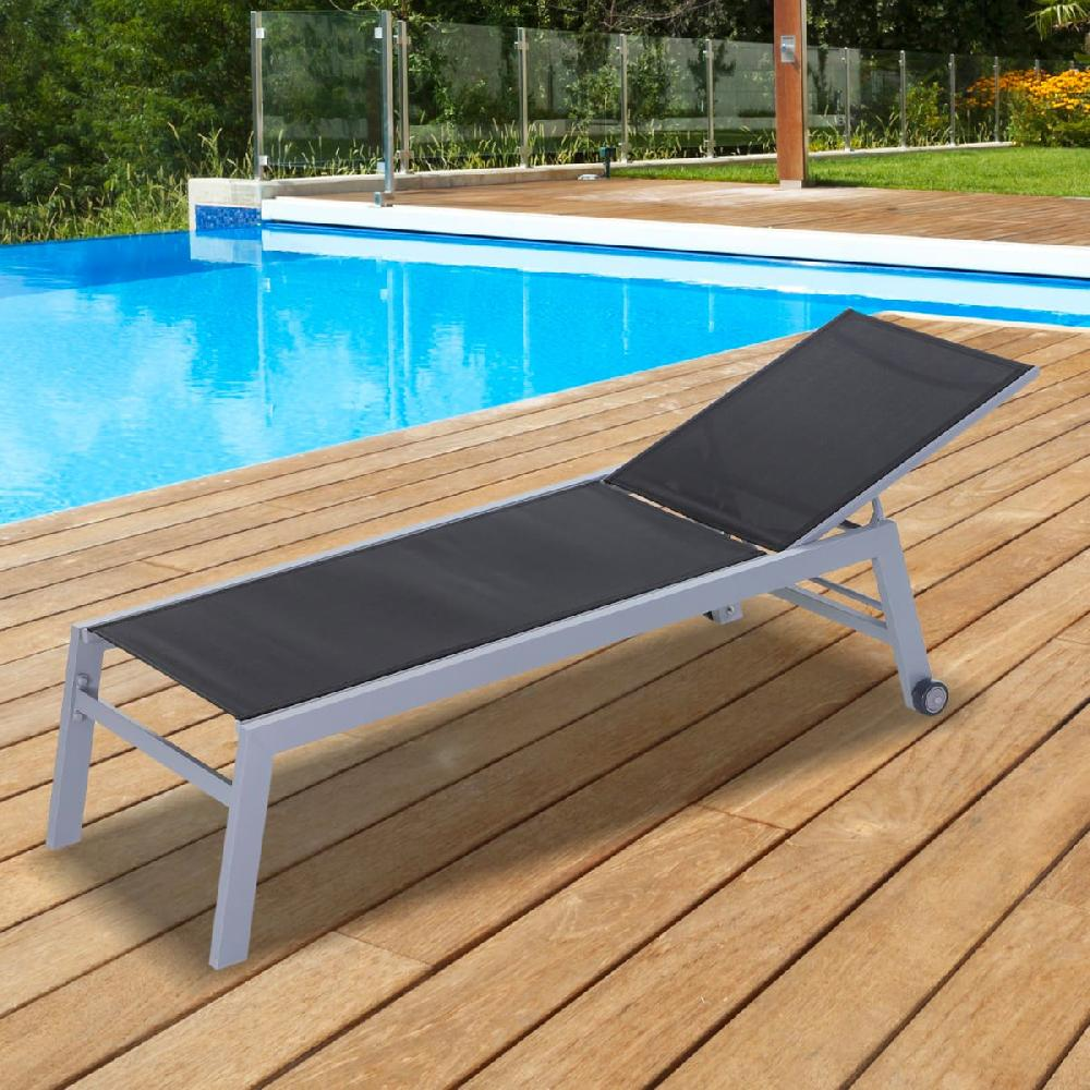 Una sdraio nera su un ponte di legno accanto a una piscina blu.