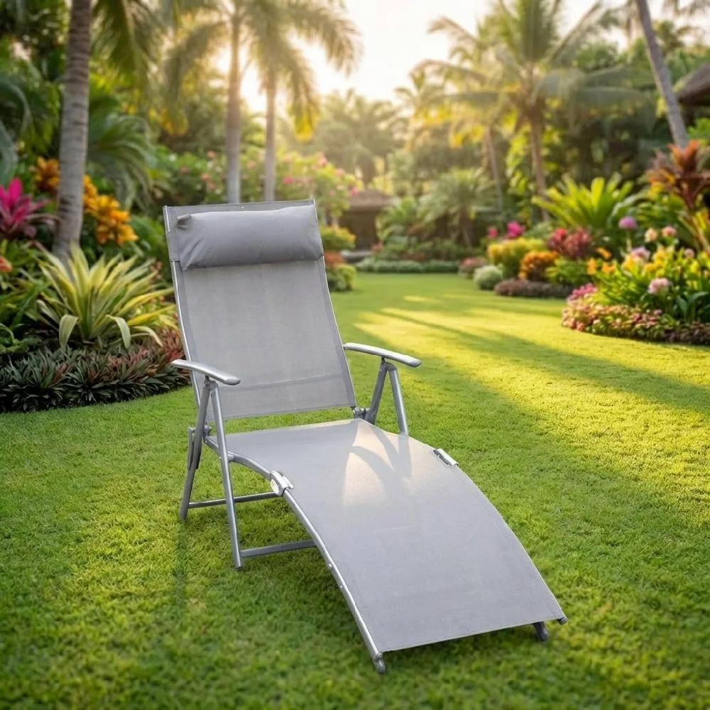 Sdraio grigio in un giardino con palme e fiori colorati alla luce del sole.