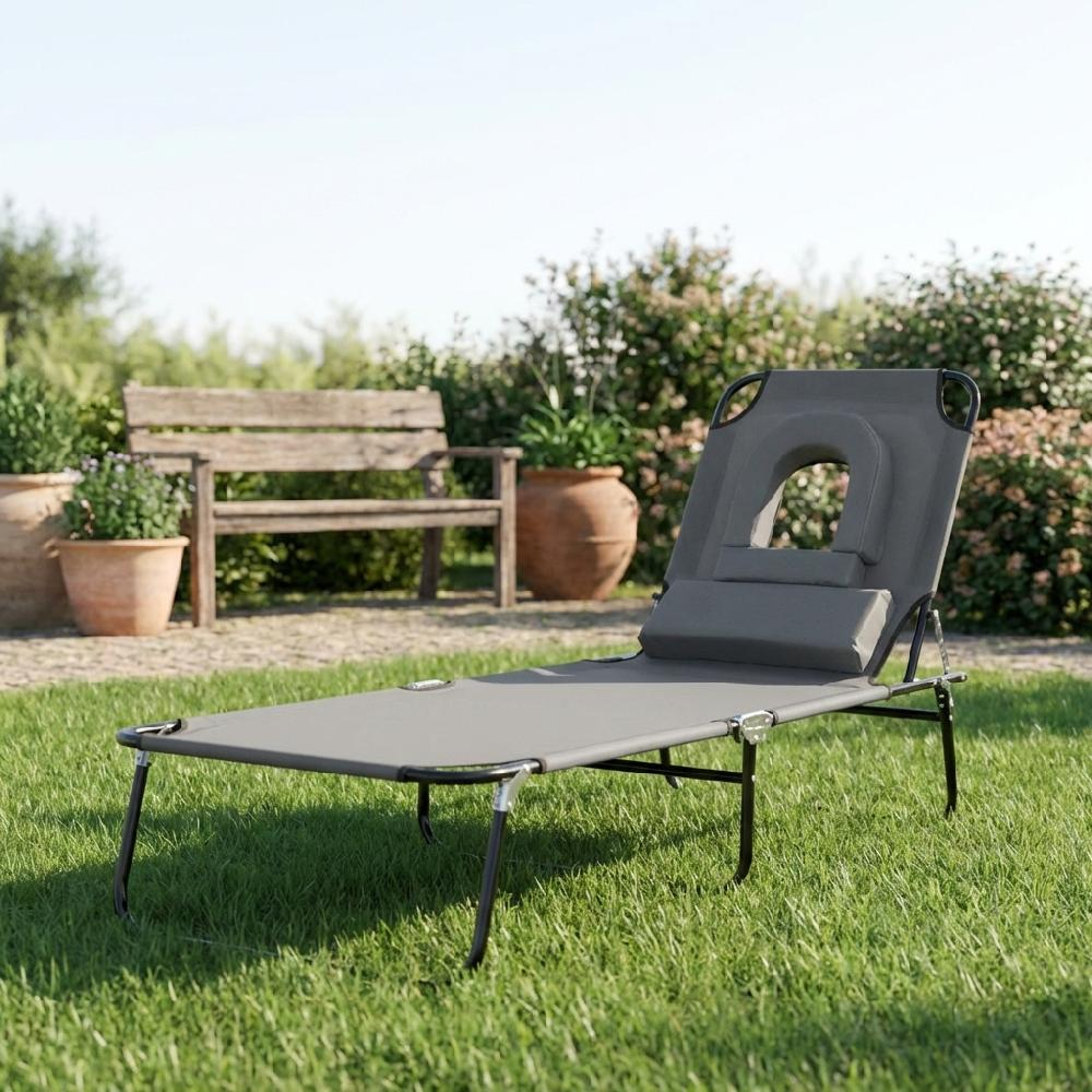 Lettino da giardino grigio con poggiatesta all'aperto sull'erba, con panca e vasi dietro.