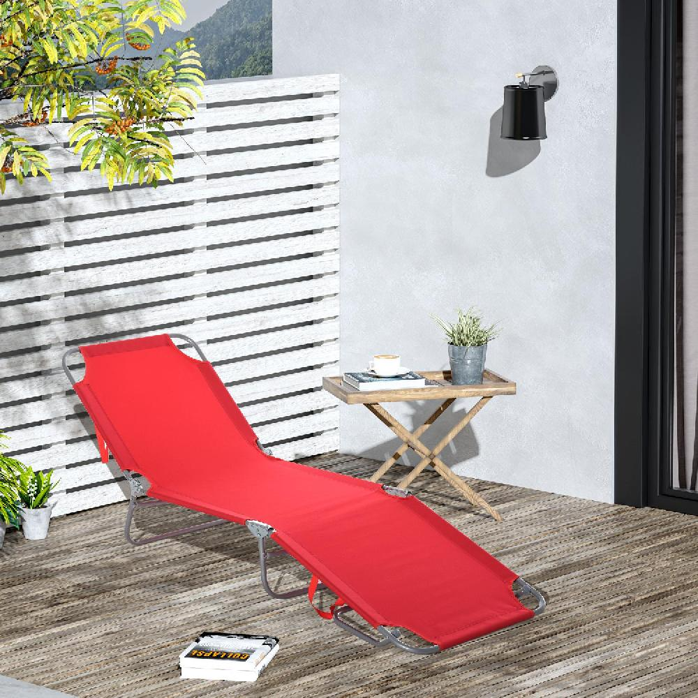 Lettino rosso su terrazza in legno con tavolino, lampada e piante.
