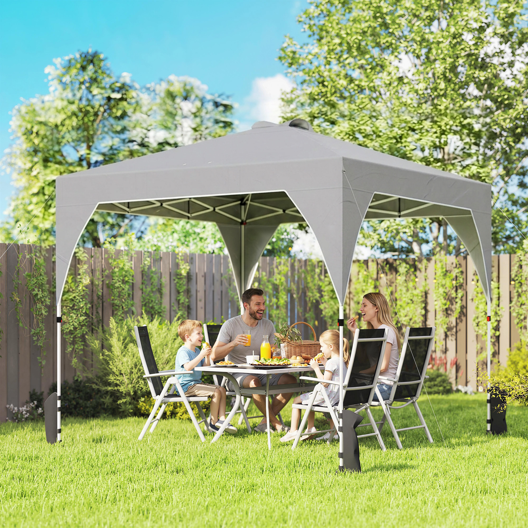 Una famiglia mangia sotto un gazebo grigio in un giardino.