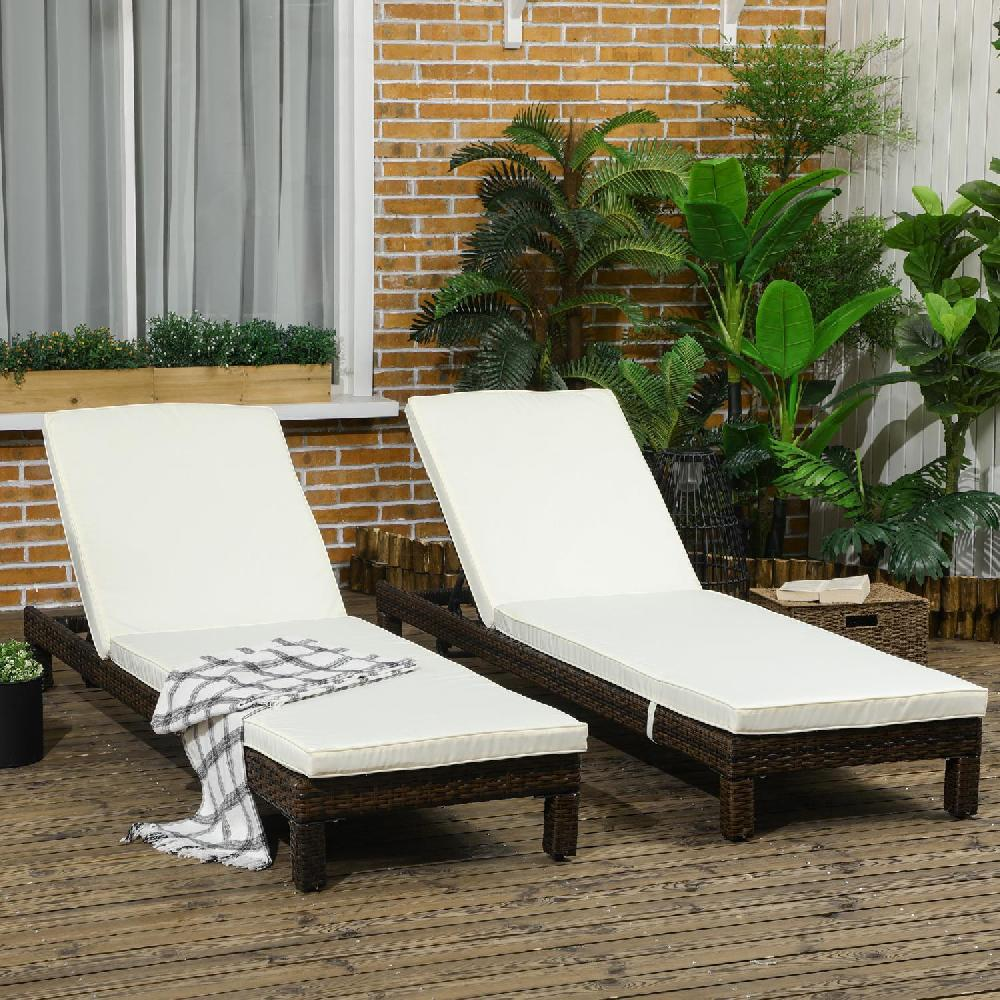 Due sedie a sdraio in vimini con cuscini bianchi su una terrazza di legno con piante.