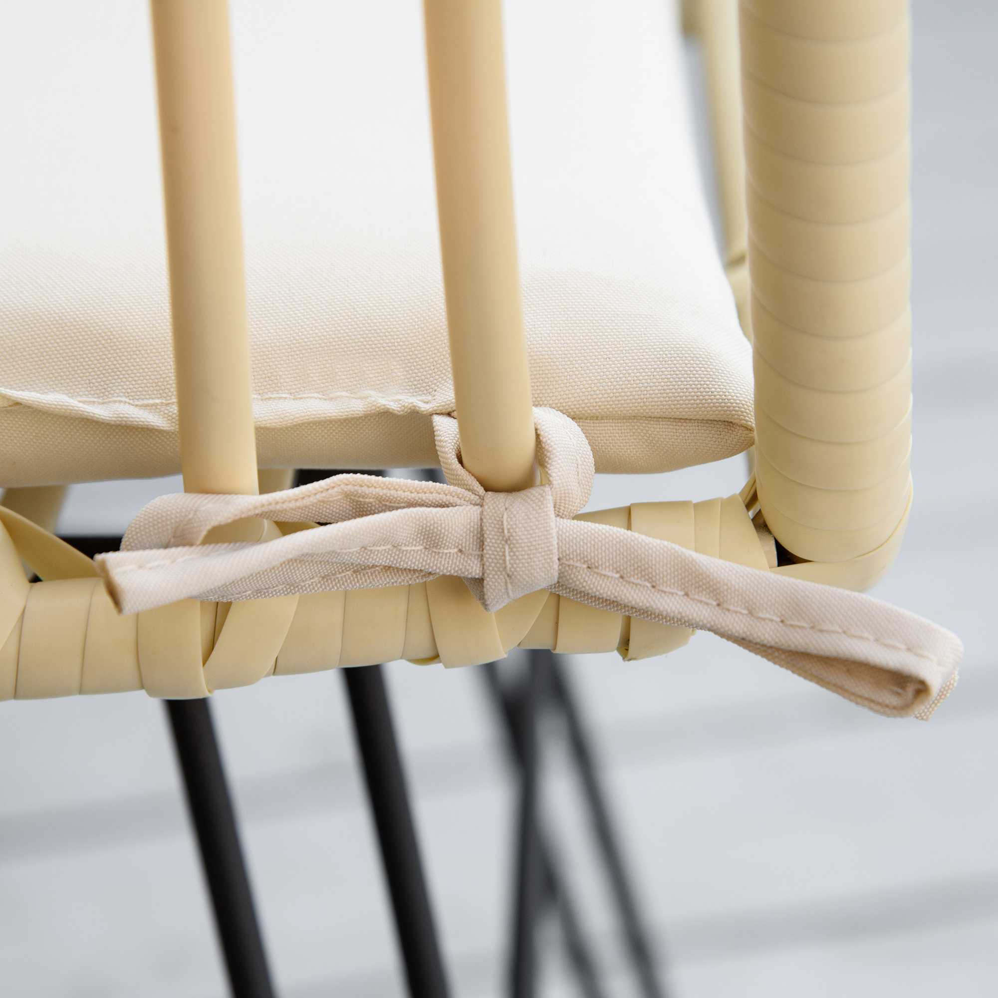 Cuscino beige su sedia in vimini con gambe nere.