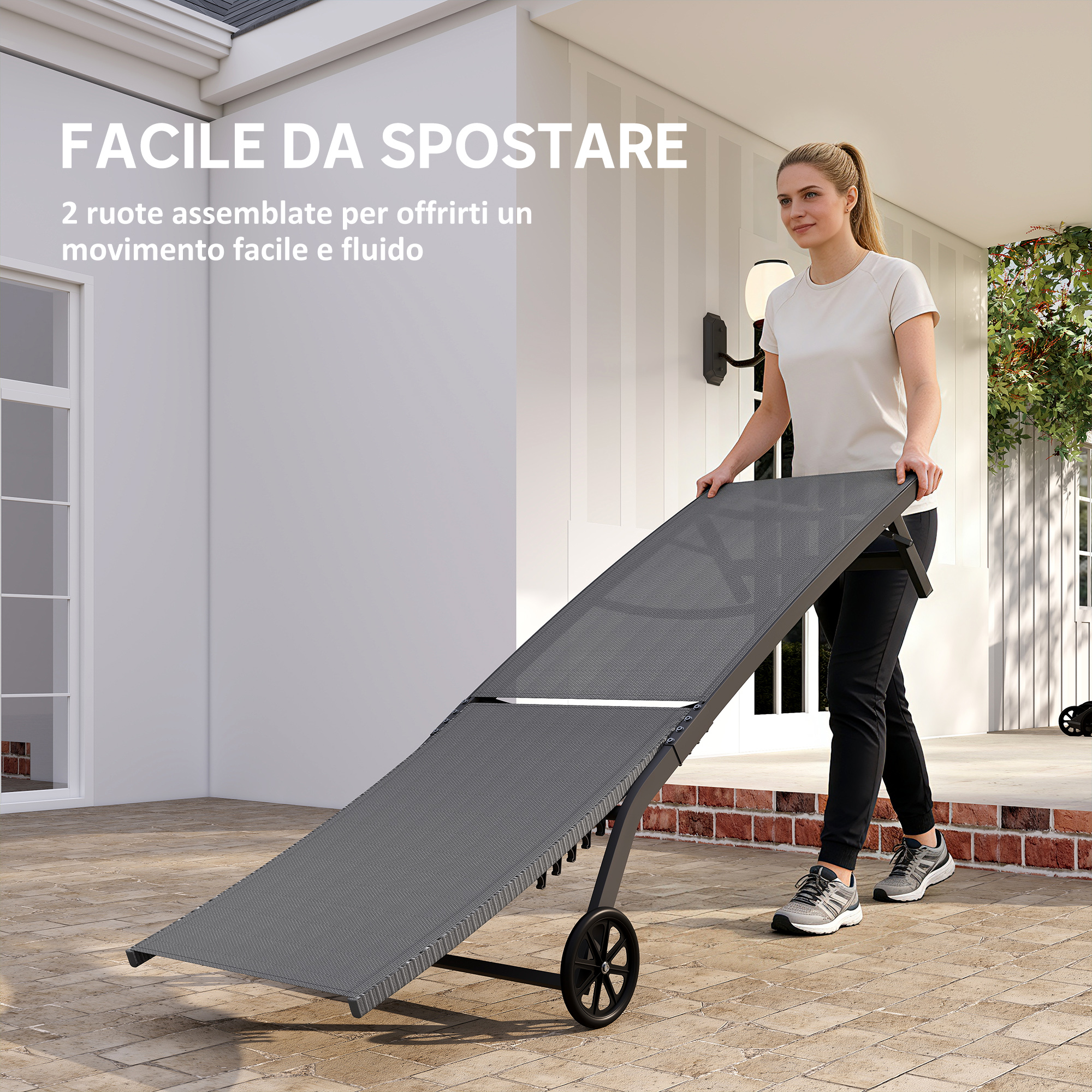 Una donna spinge una sdraio grigia con ruote su un patio pavimentato.
