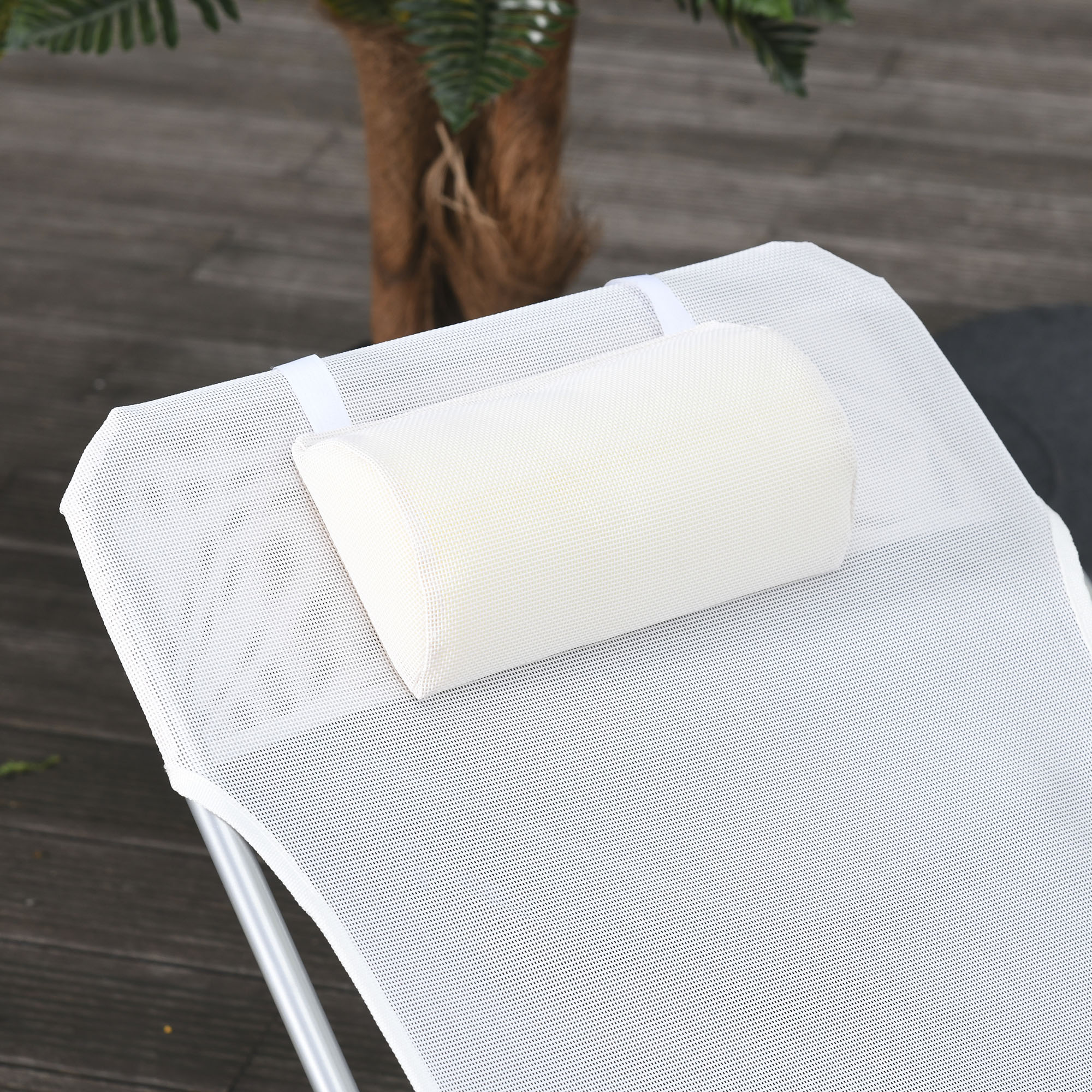 Un cuscino bianco su una sedia in rete bianca su assi di legno.