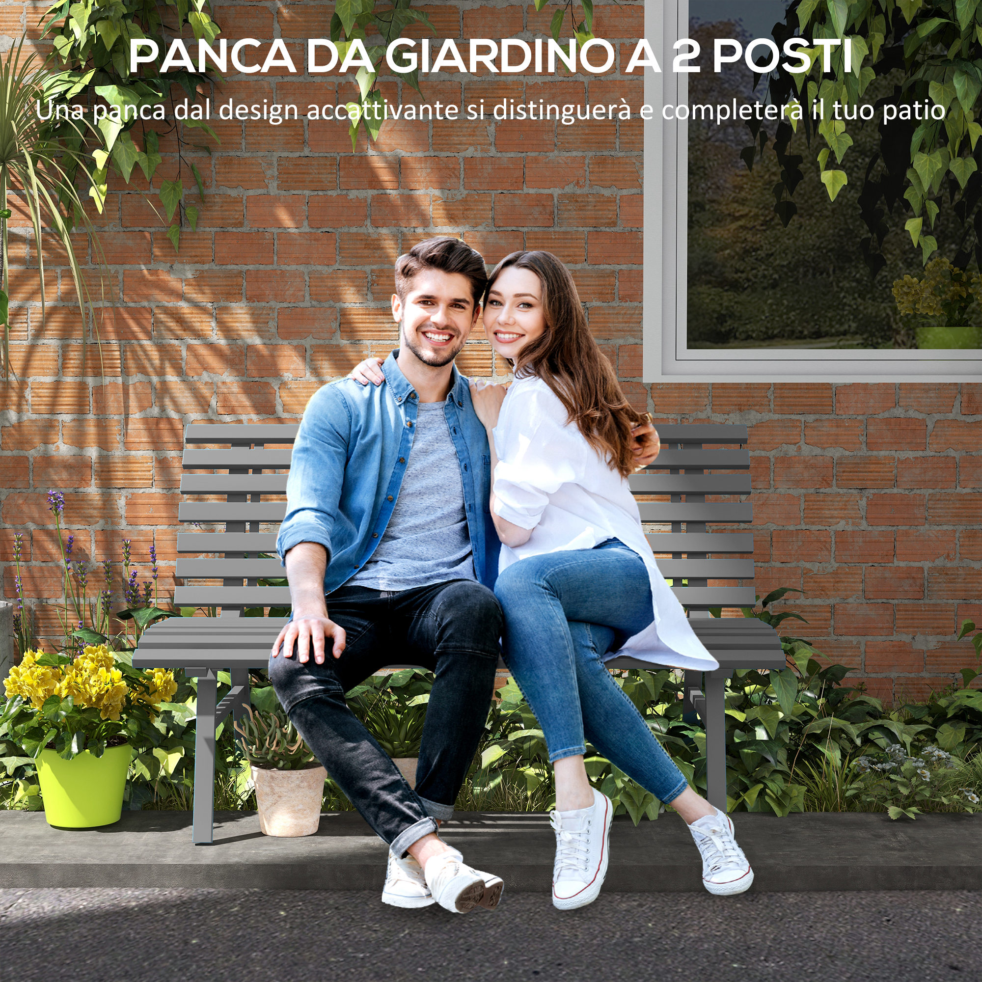 Una coppia siede su una panchina da giardino grigia davanti a un muro di mattoni.