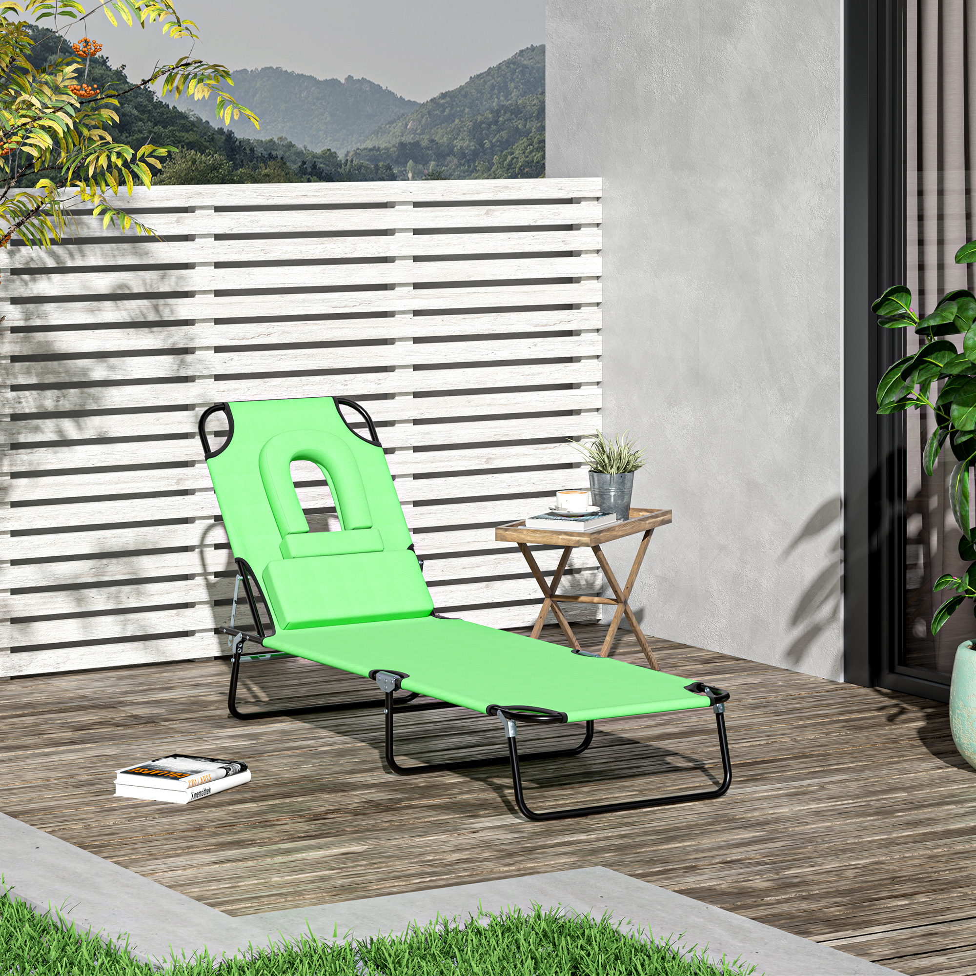 Una sdraio verde su un ponte di legno con libri e un tavolo.