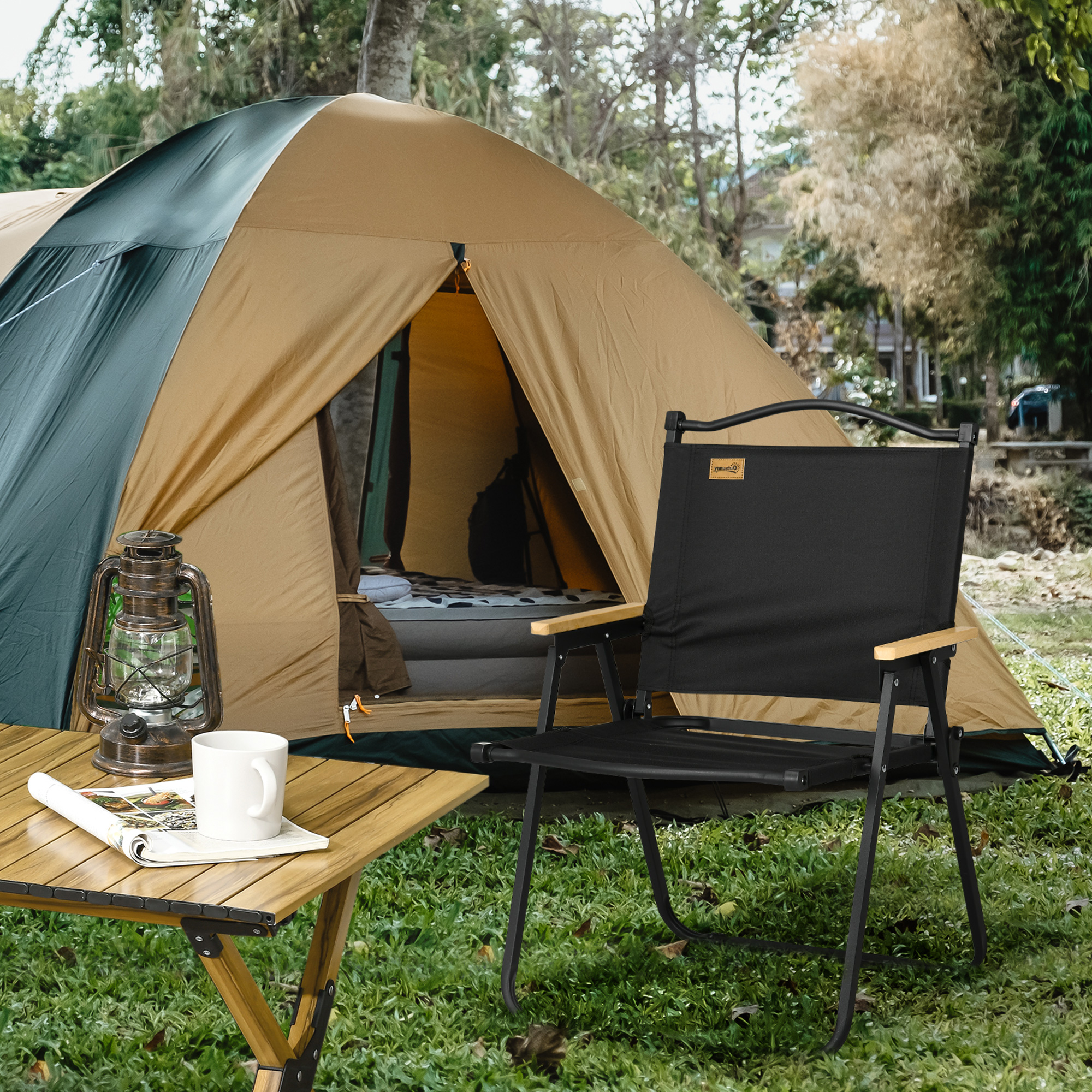 Una tenda color cachi, una sedia nera, una lanterna e un tavolo con tazza e rivista all'aperto.