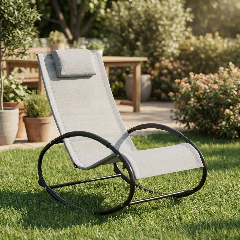 Una sedia a dondolo grigio chiaro con poggiatesta è seduta sull'erba verde in un giardino.