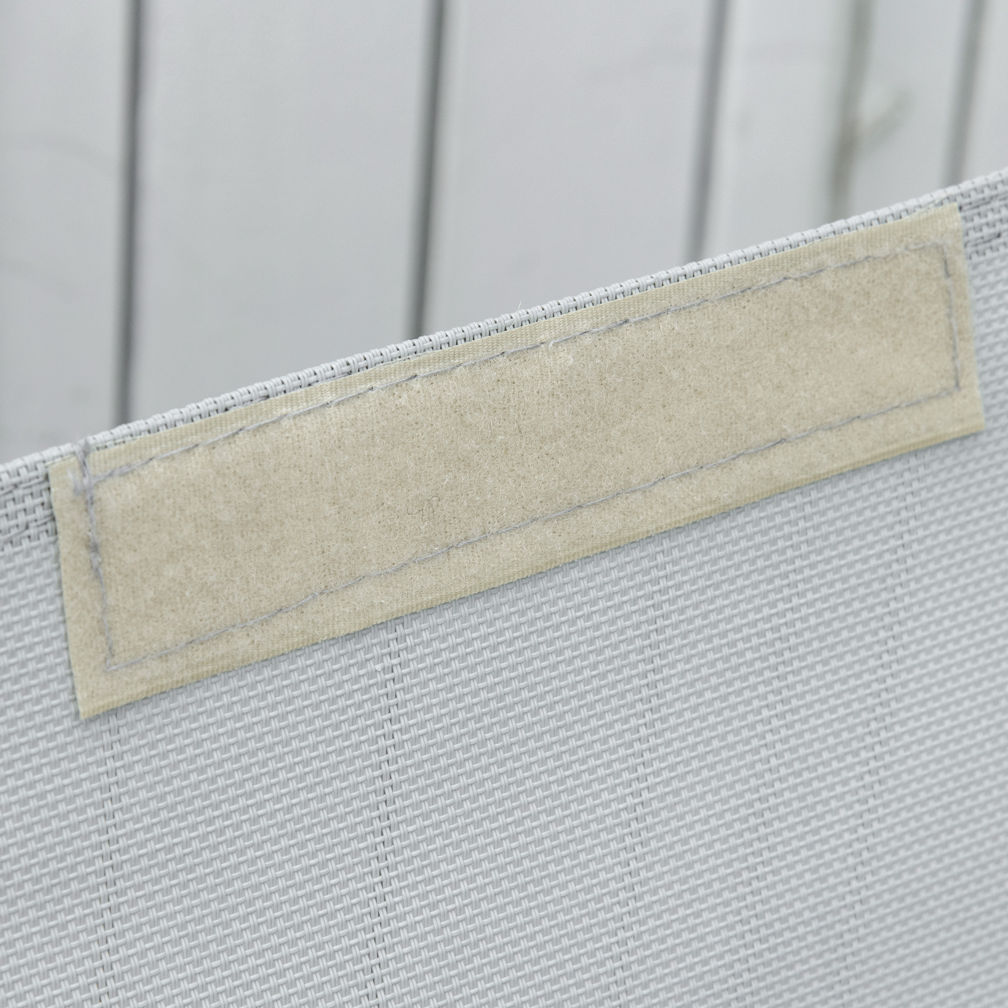 Cesto in tessuto grigio con striscia in velcro. Venature di legno sullo sfondo.